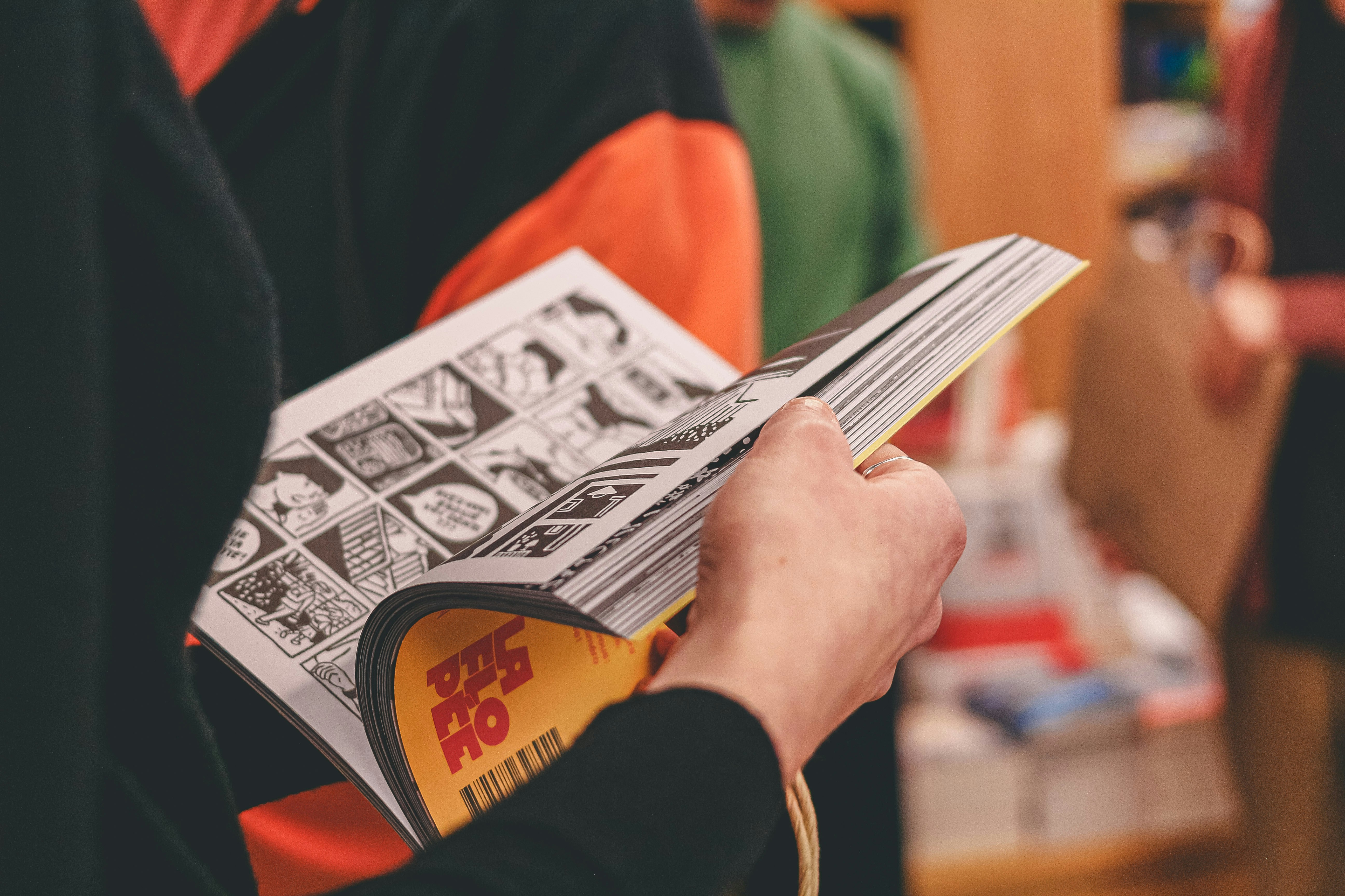 Person flipping through a comic book with panels.