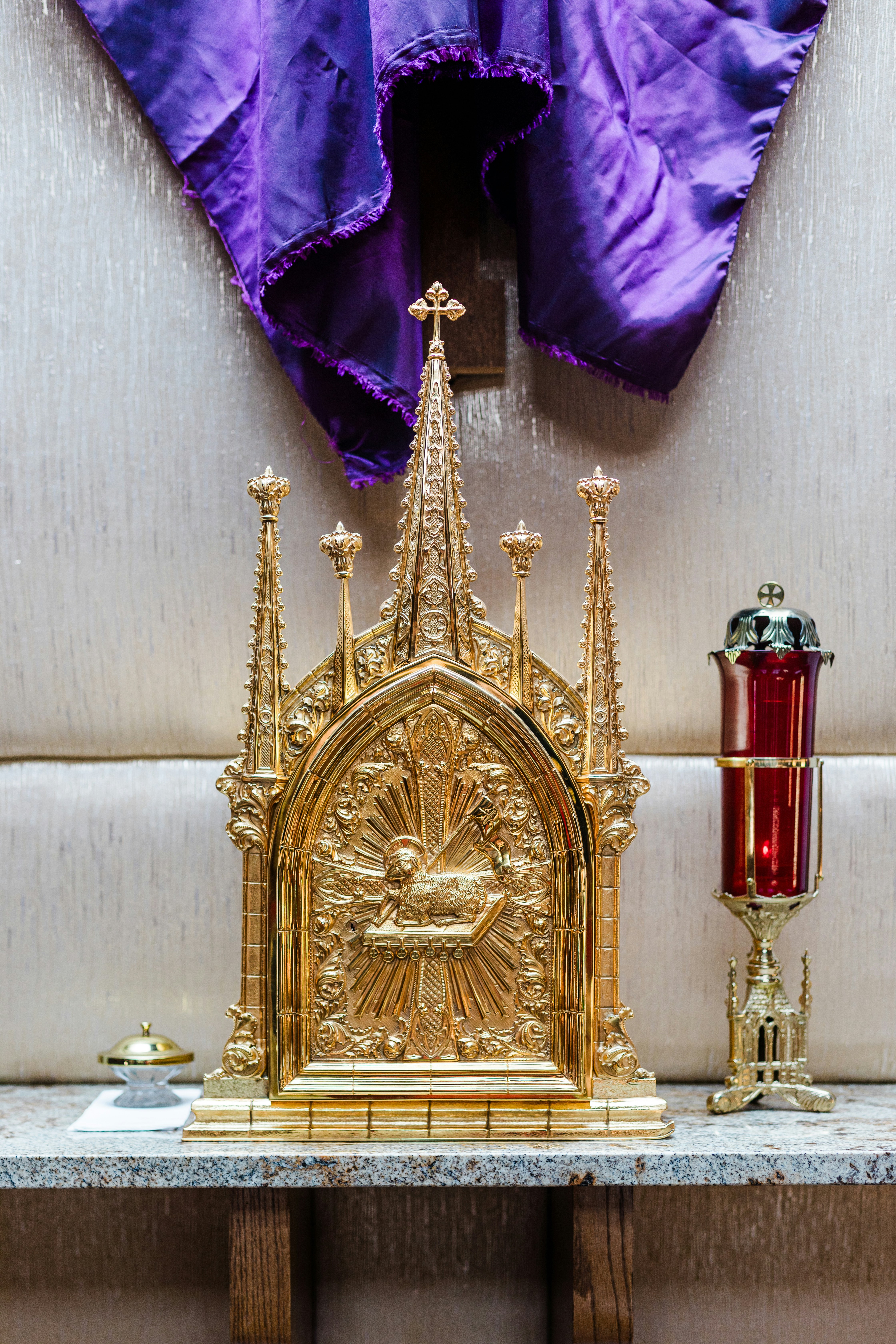 Un ornamentado tabernáculo dorado con una vela votiva roja.