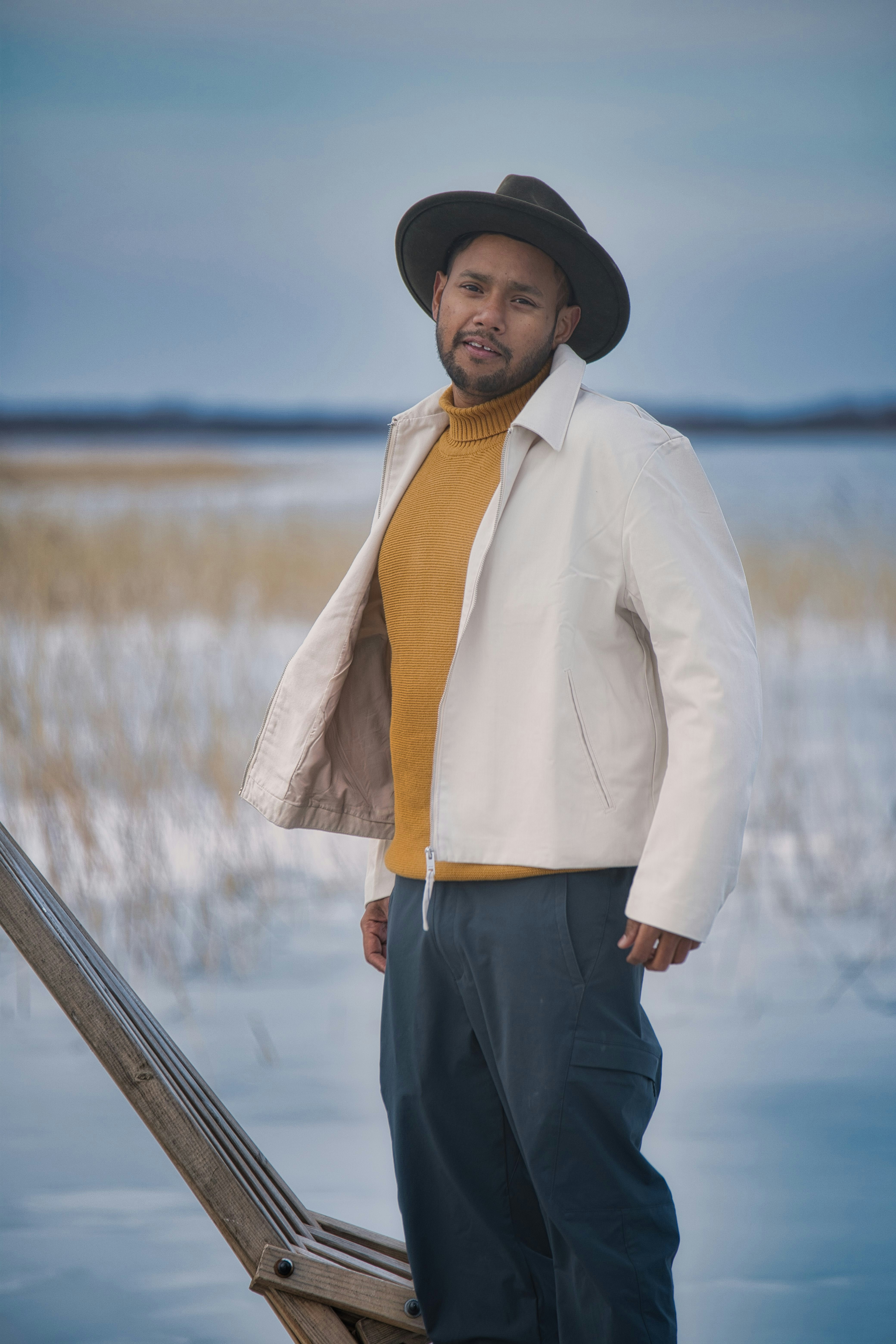 Uomo con cappello e dolcevita giallo nel paesaggio invernale