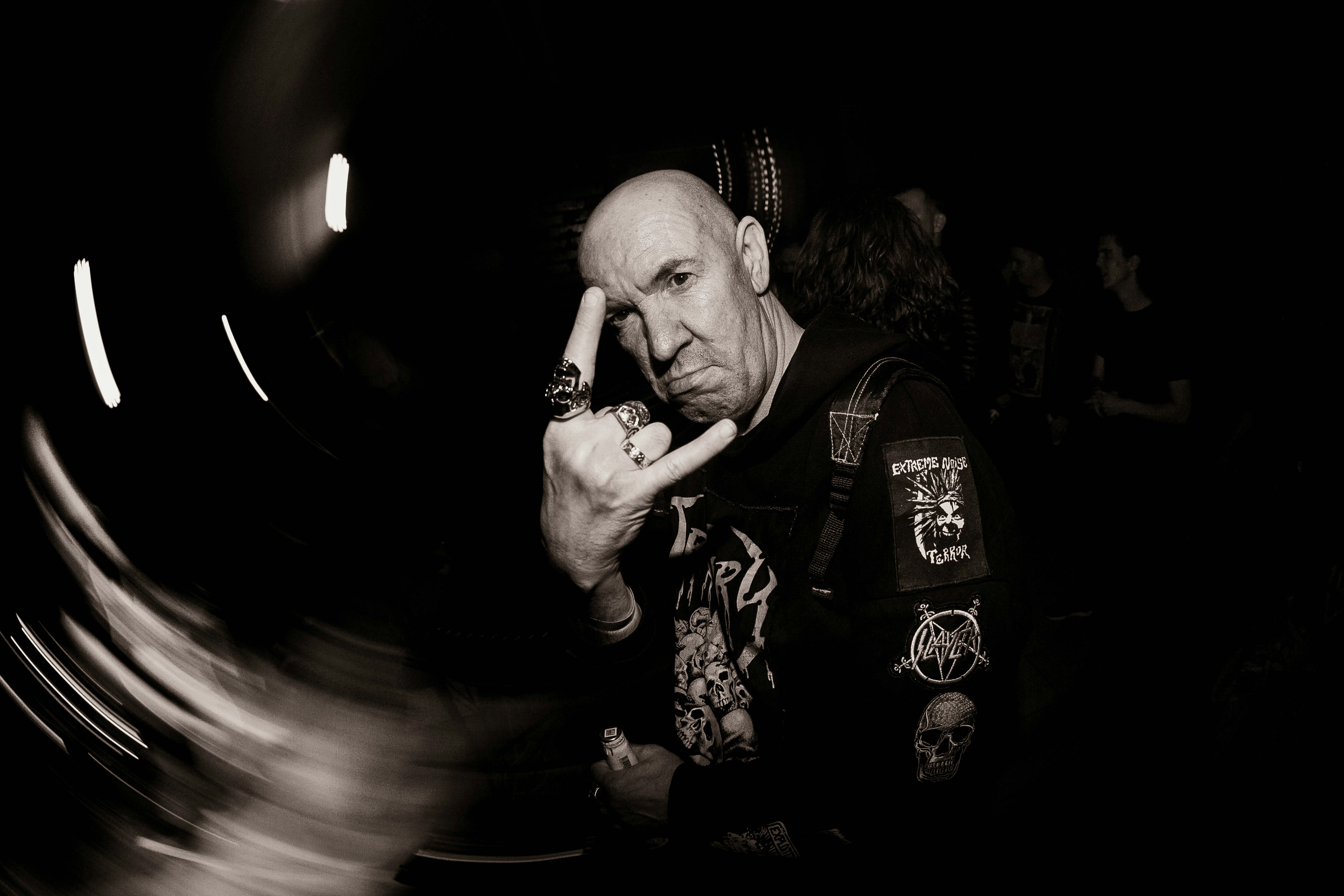 Glatzköpfiger Mann mit Kinnbart macht Steinhörner, Handbewegung