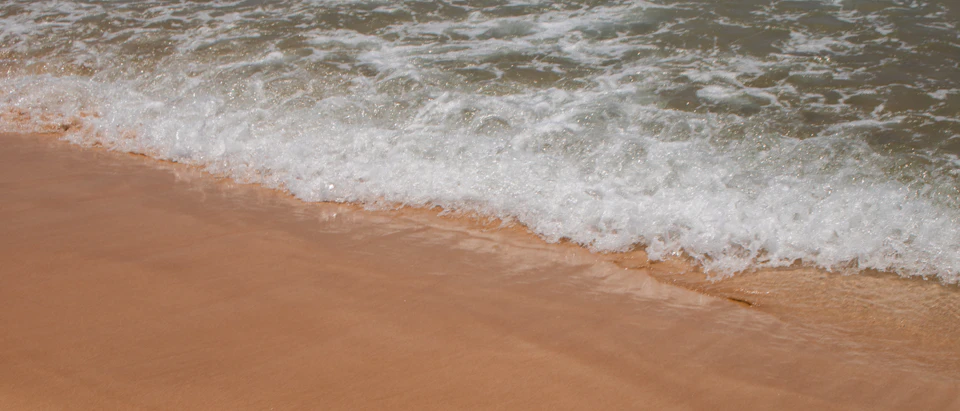 Serene beach scene with waves rolling onto light brown sand at an angle