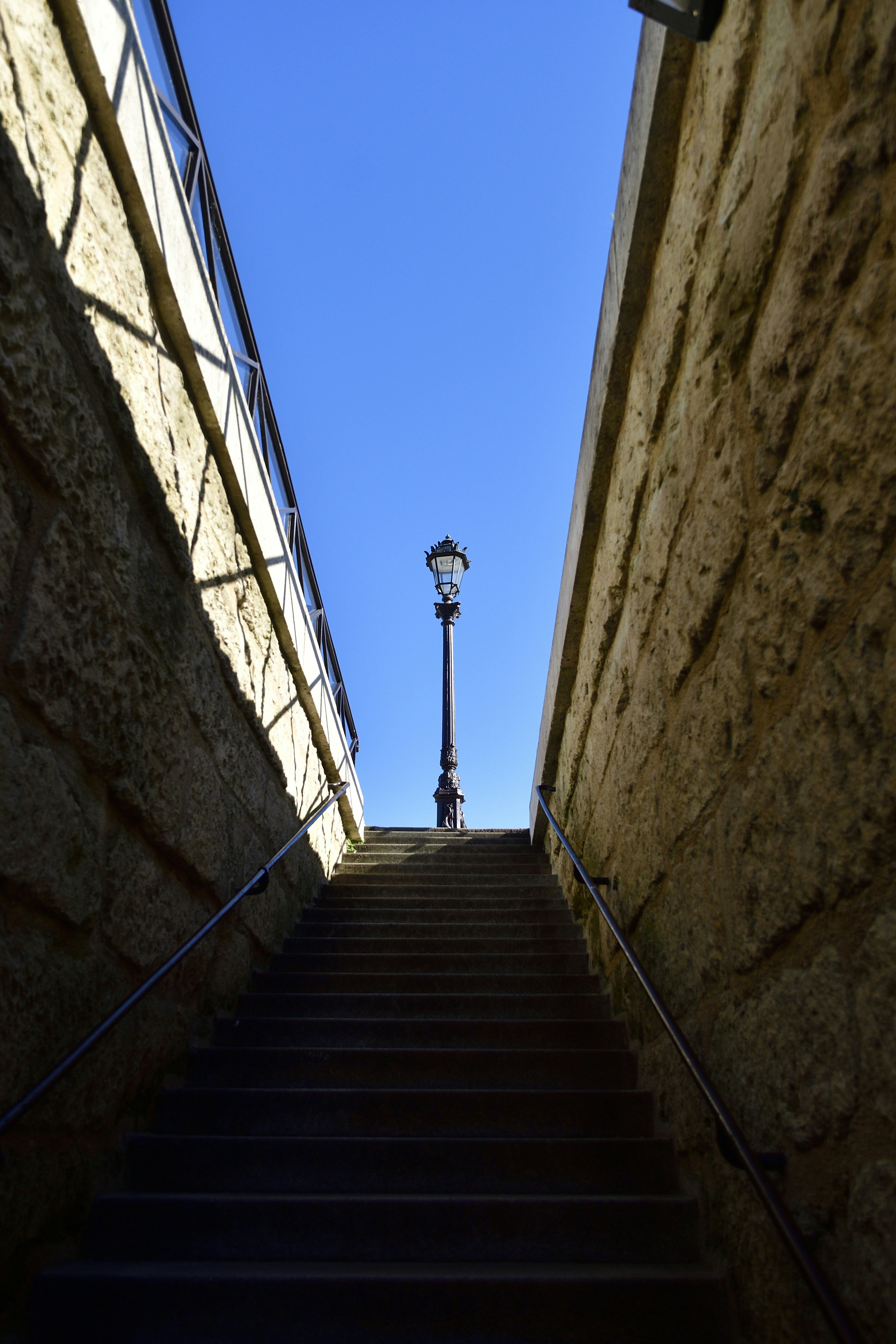 Stone stairs lead up to a lamppost under blue sky