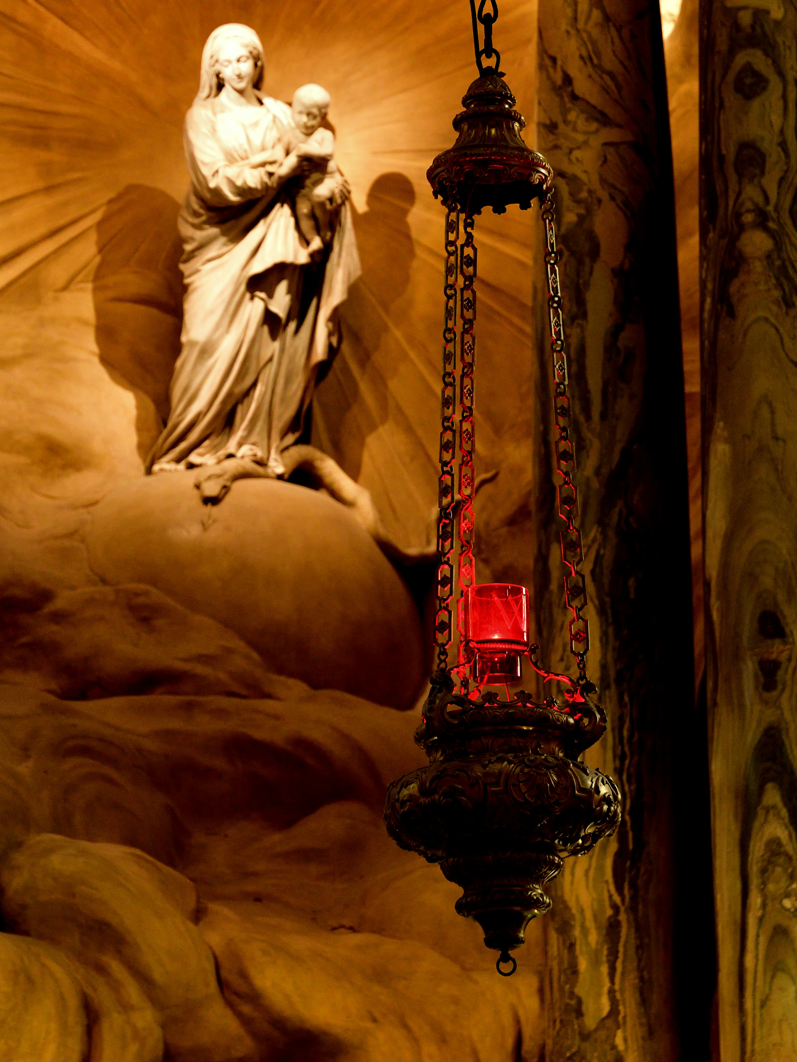 Statue of mary holding baby jesus with hanging lamp