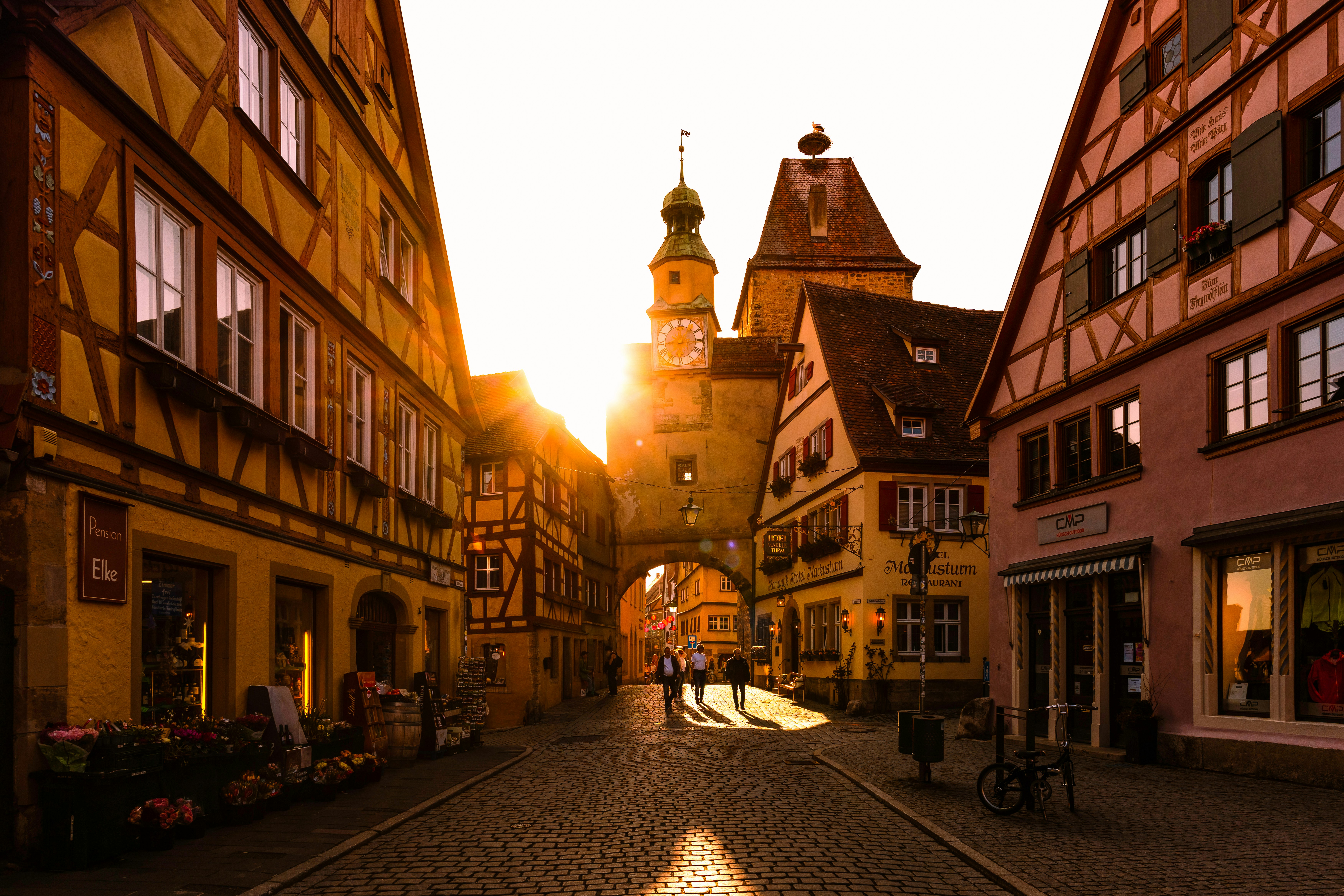 Sunlit medieval street with half-timbered houses and colorful buildings.