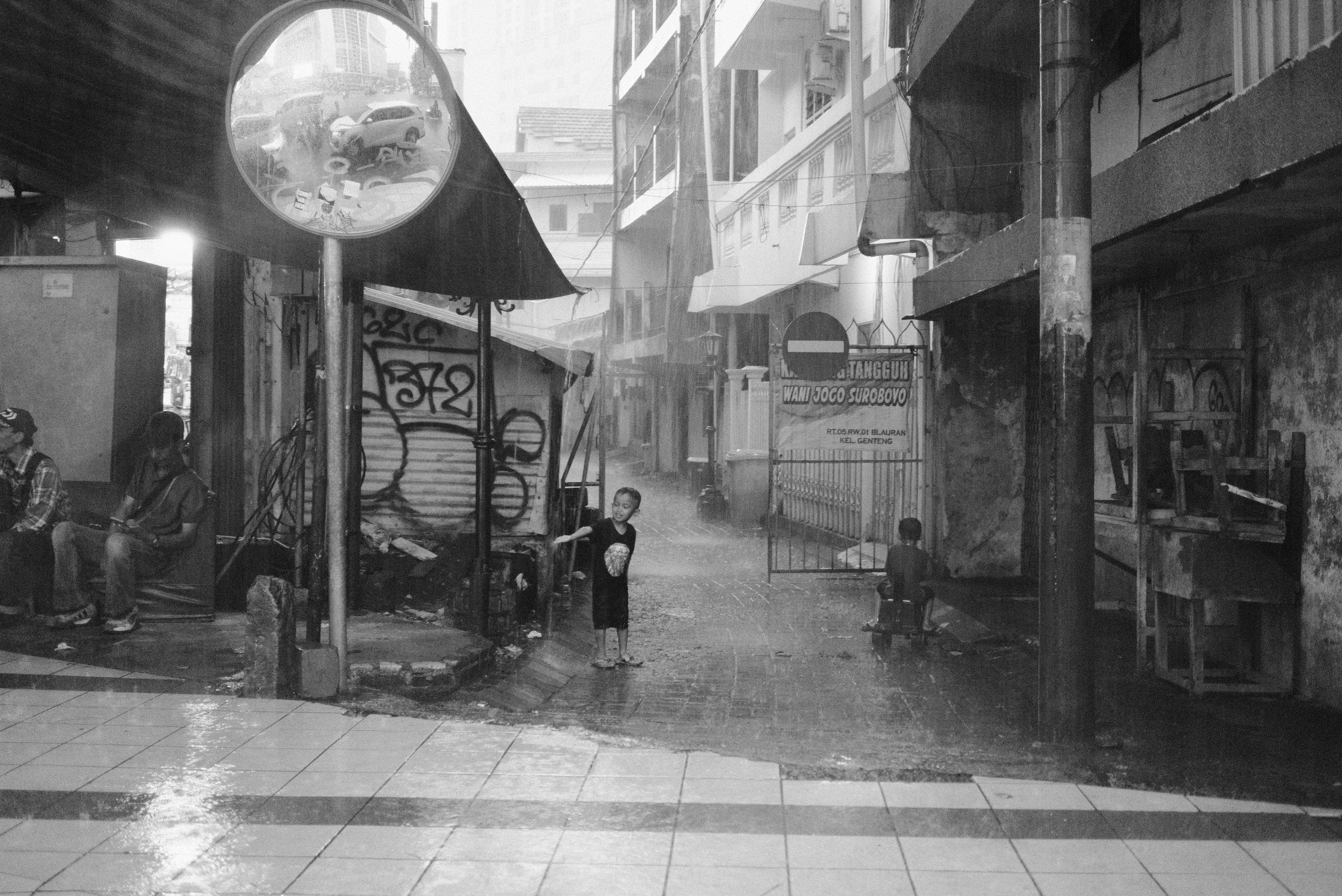雨の降る路地で遊ぶ子供たち