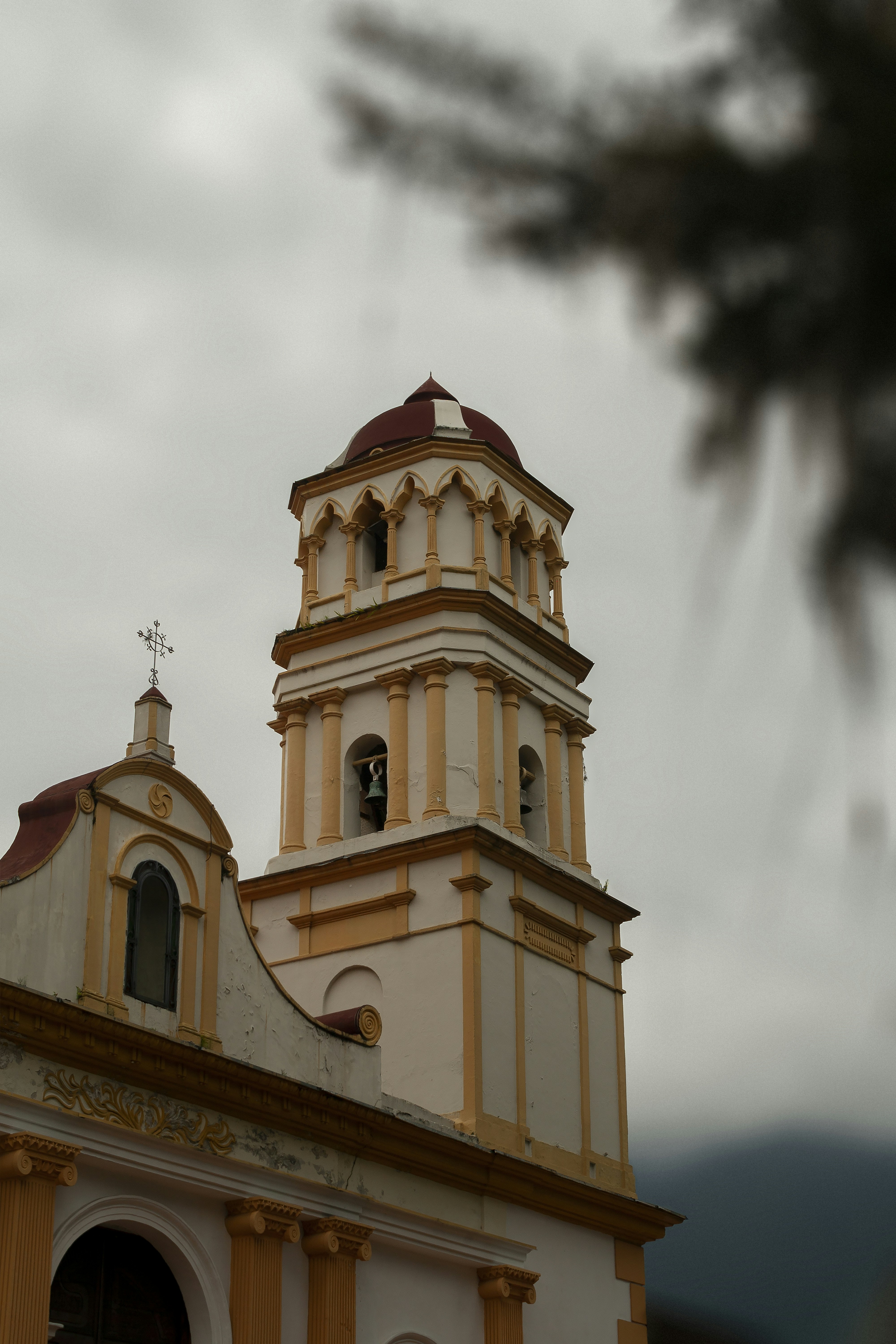 Ornate church tower with red dome against cloudy sky