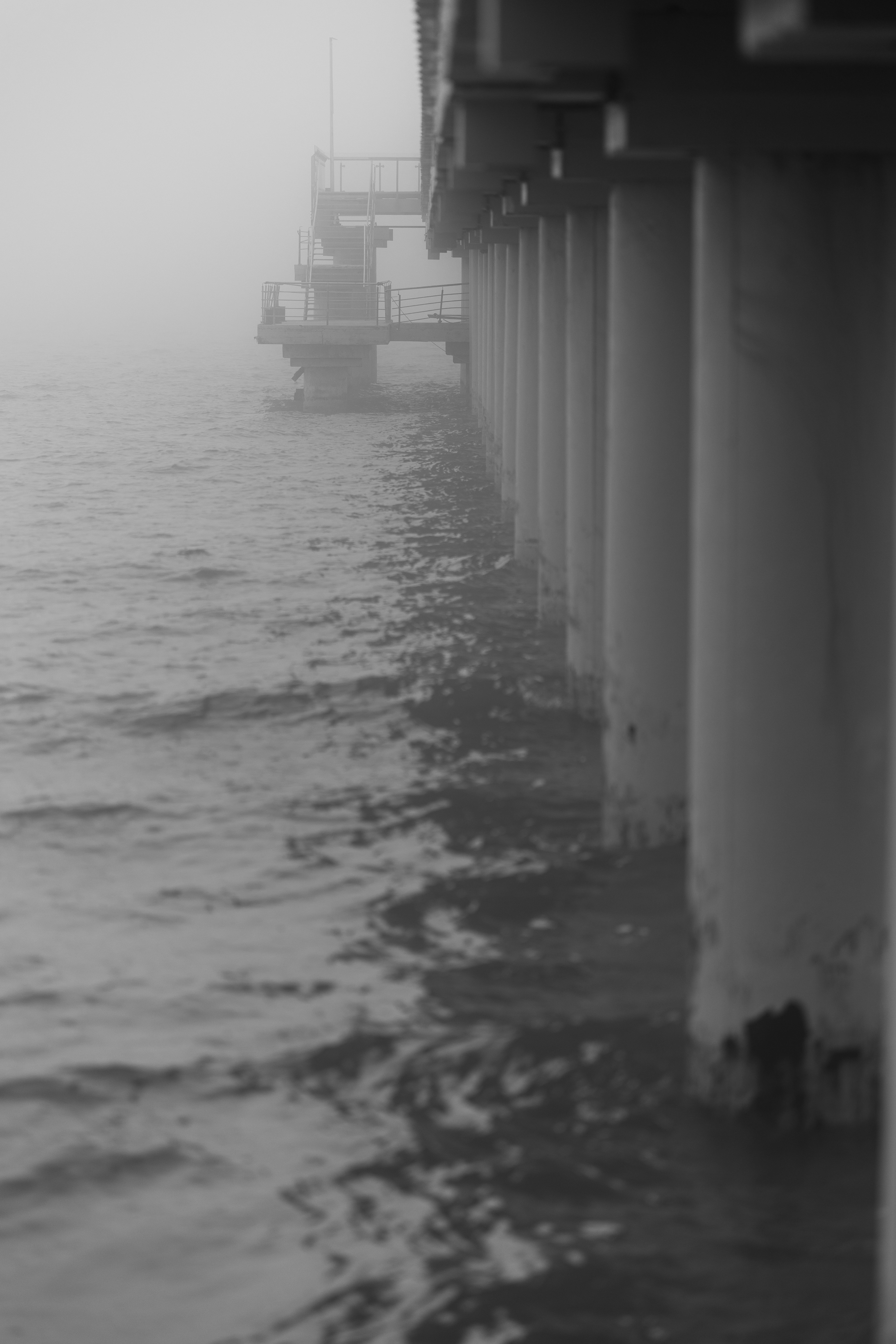 Pier posts in fog over rippling water