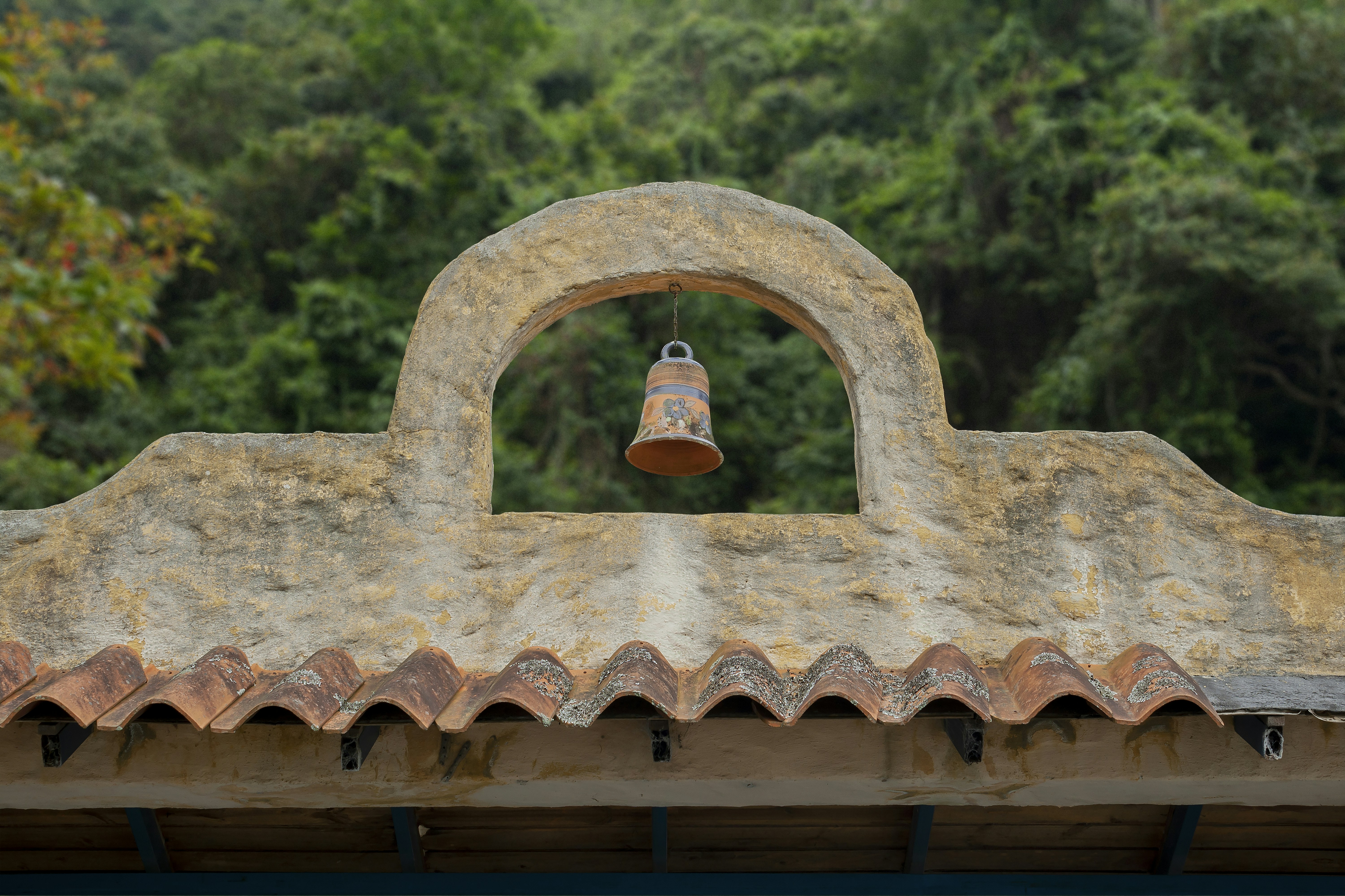 A bell hangs from an arched entryway.
