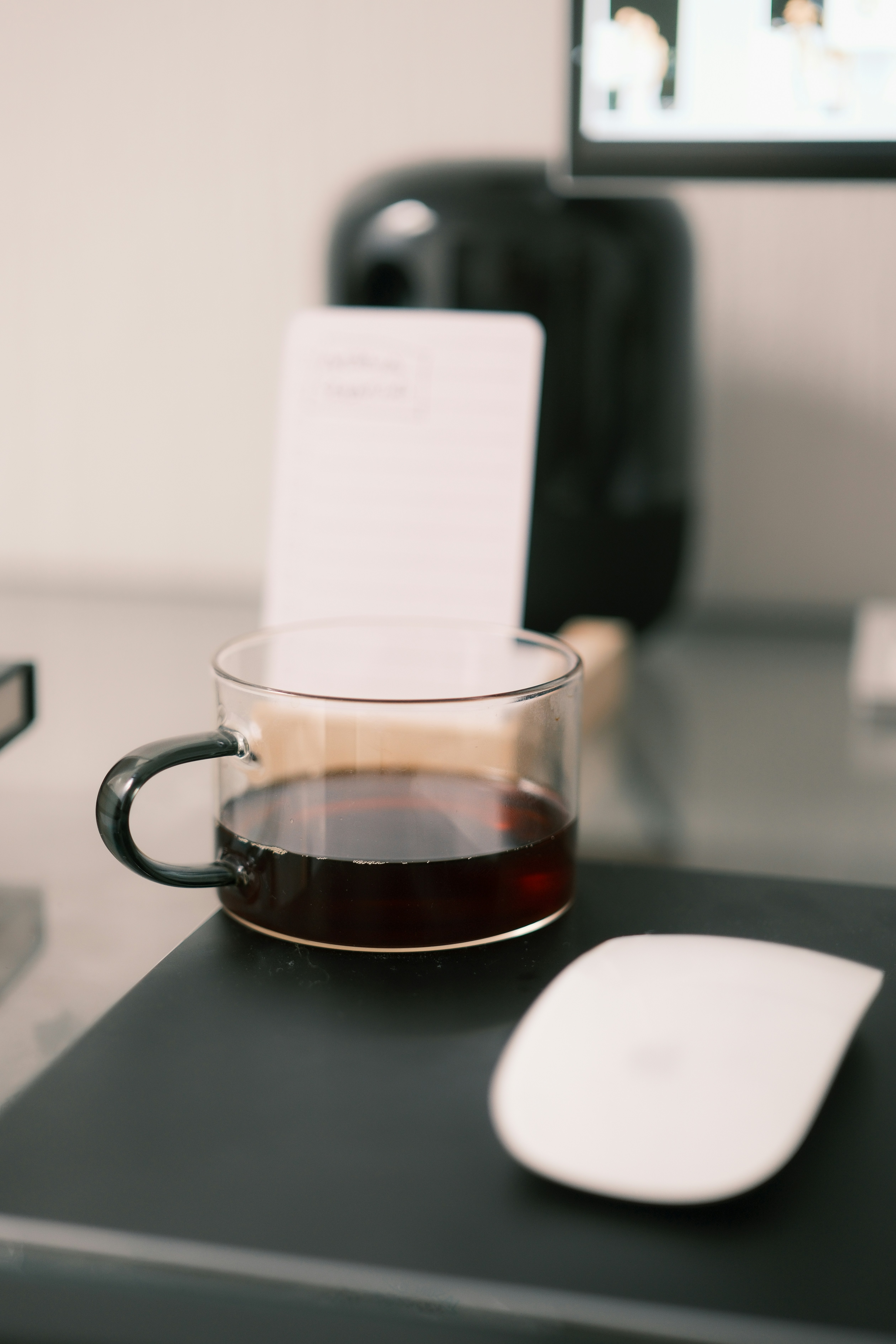 Eine klare Tasse dunklen Kaffees steht auf einem Schreibtisch.