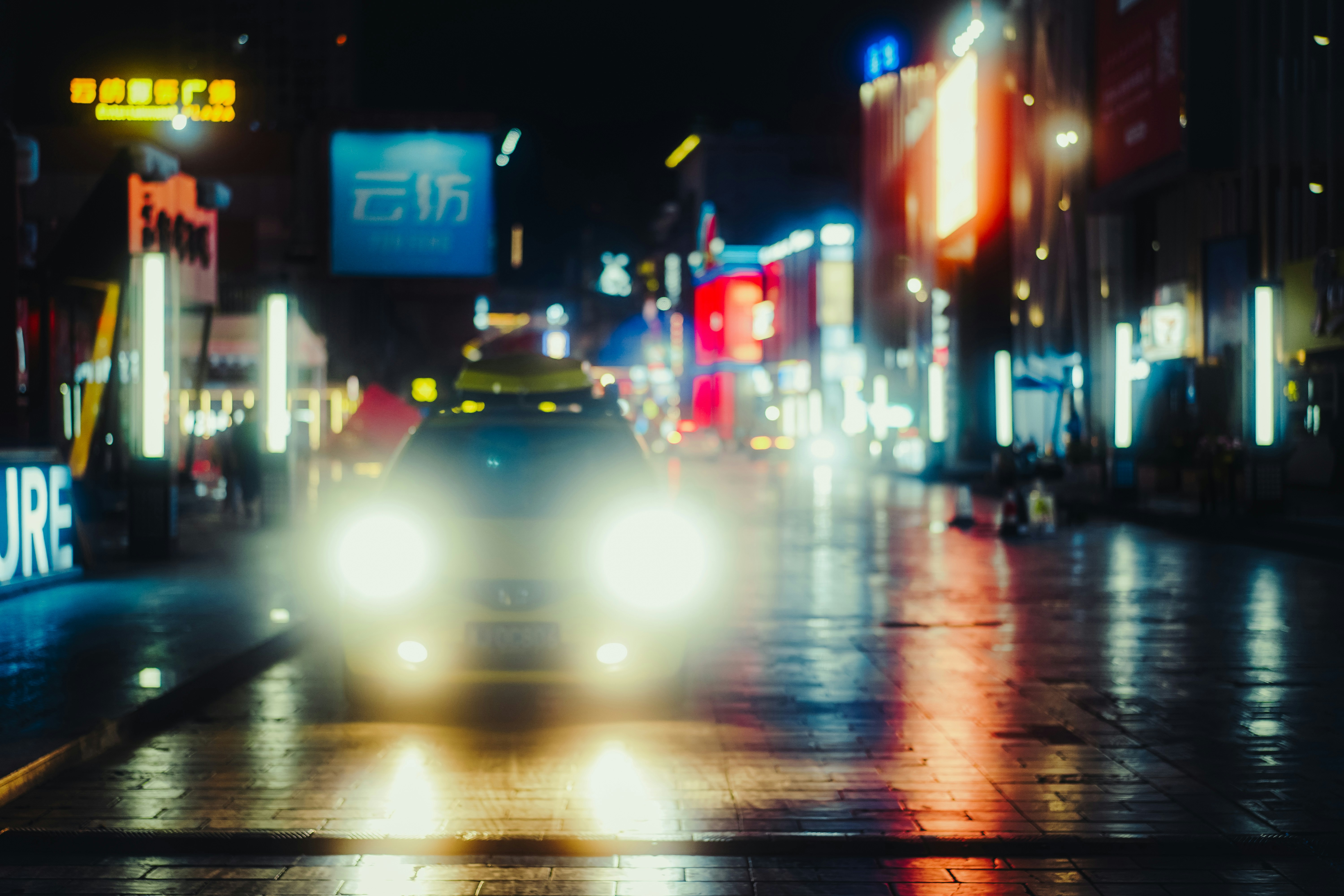 Coche conduciendo por una calle mojada de la ciudad de noche