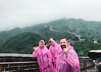 Three people in pink raincoats on a misty mountain.