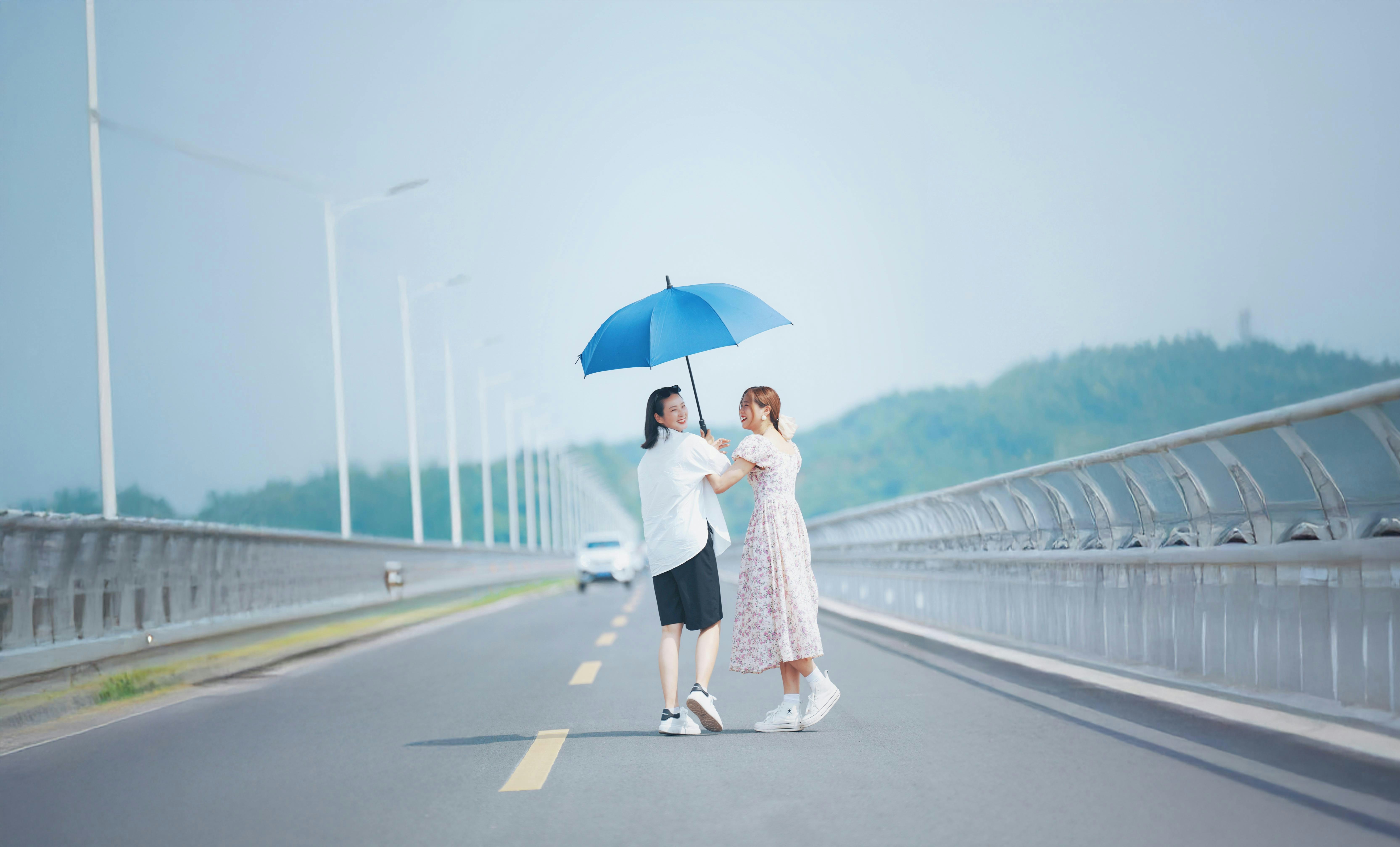 Due donne condividono un ombrello su una strada.