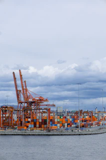 Orange cranes and shipping containers at a busy port.