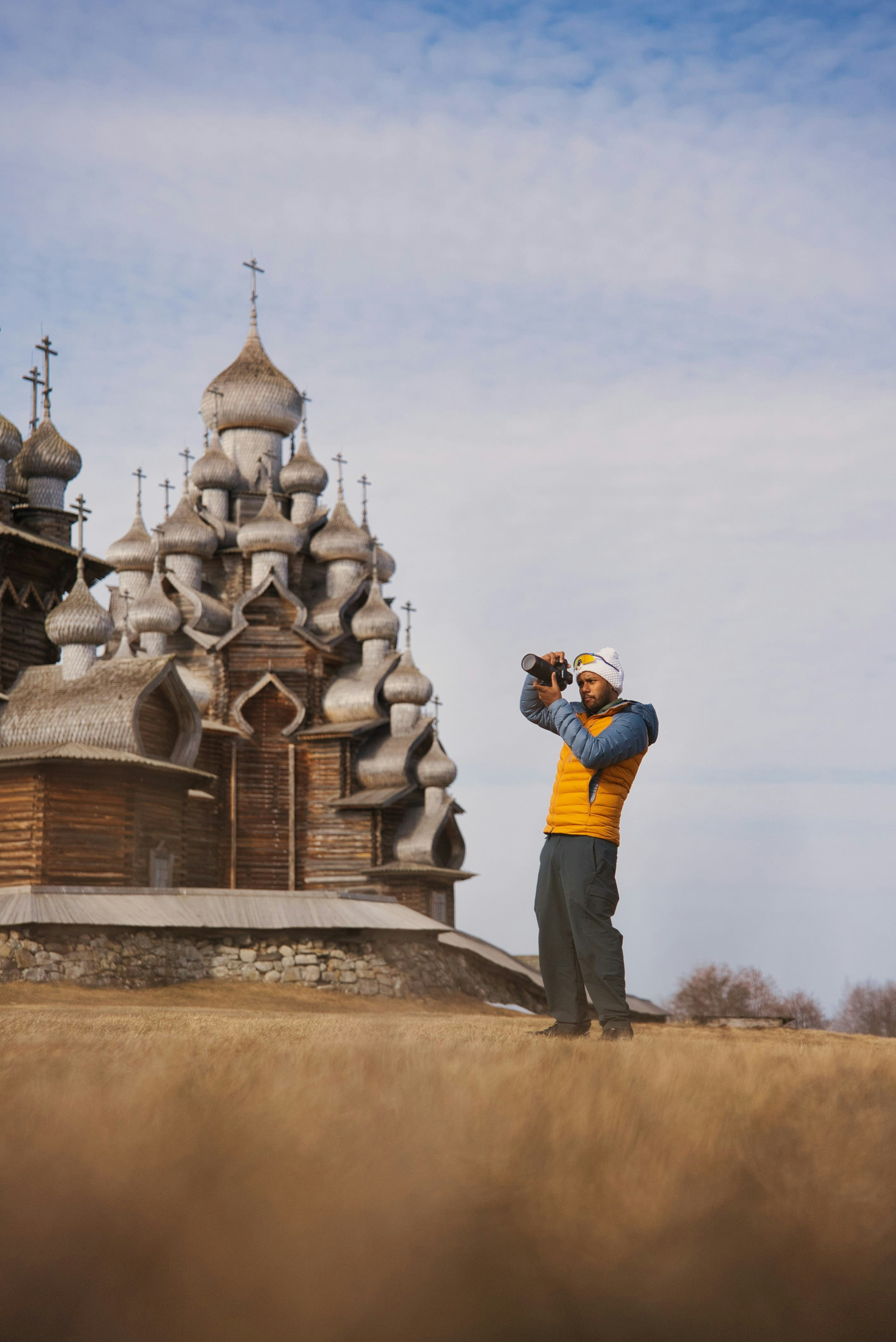 Uomo fotografa una chiesa di legno su una collina erbosa