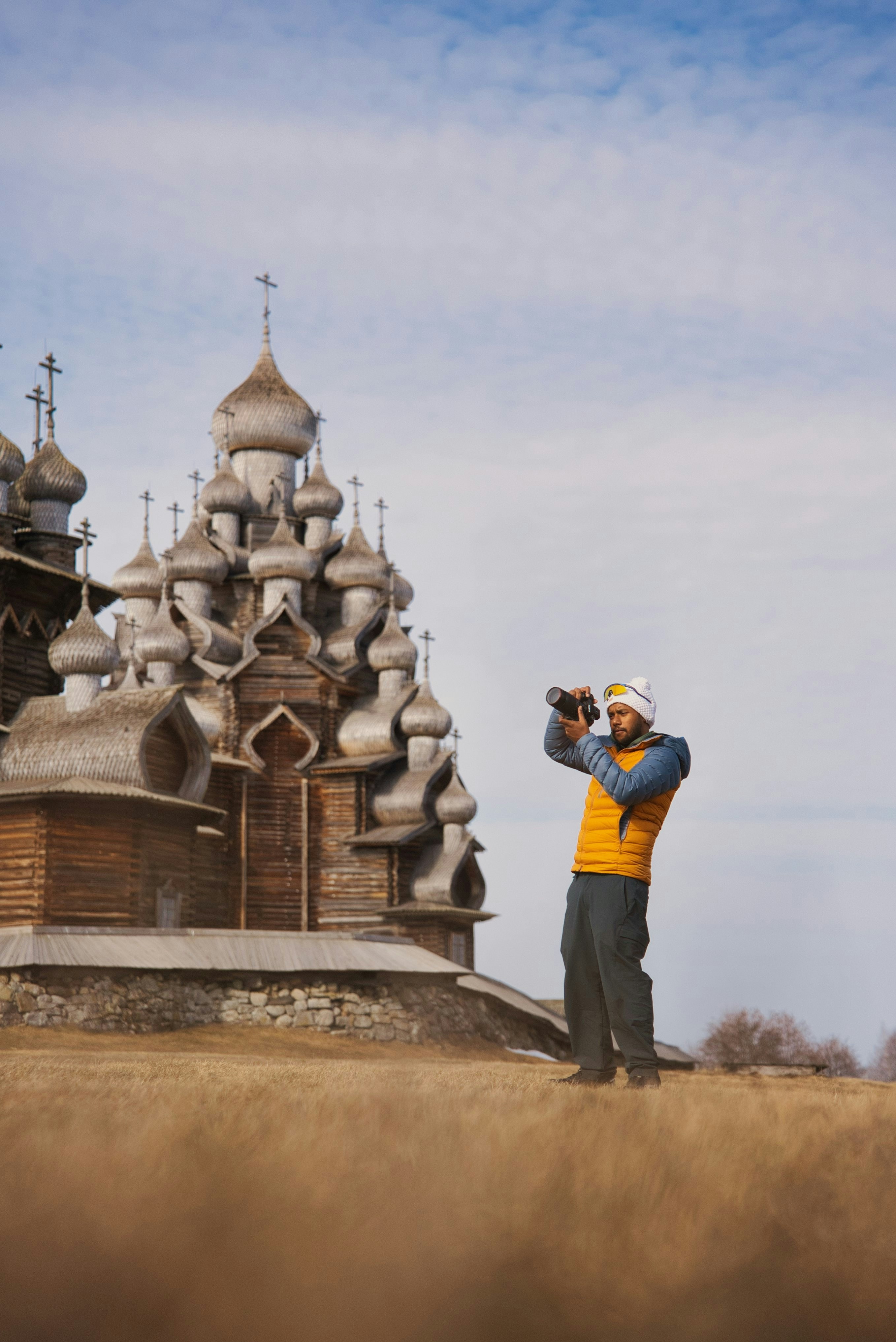 Uomo fotografa una chiesa di legno su una collina erbosa