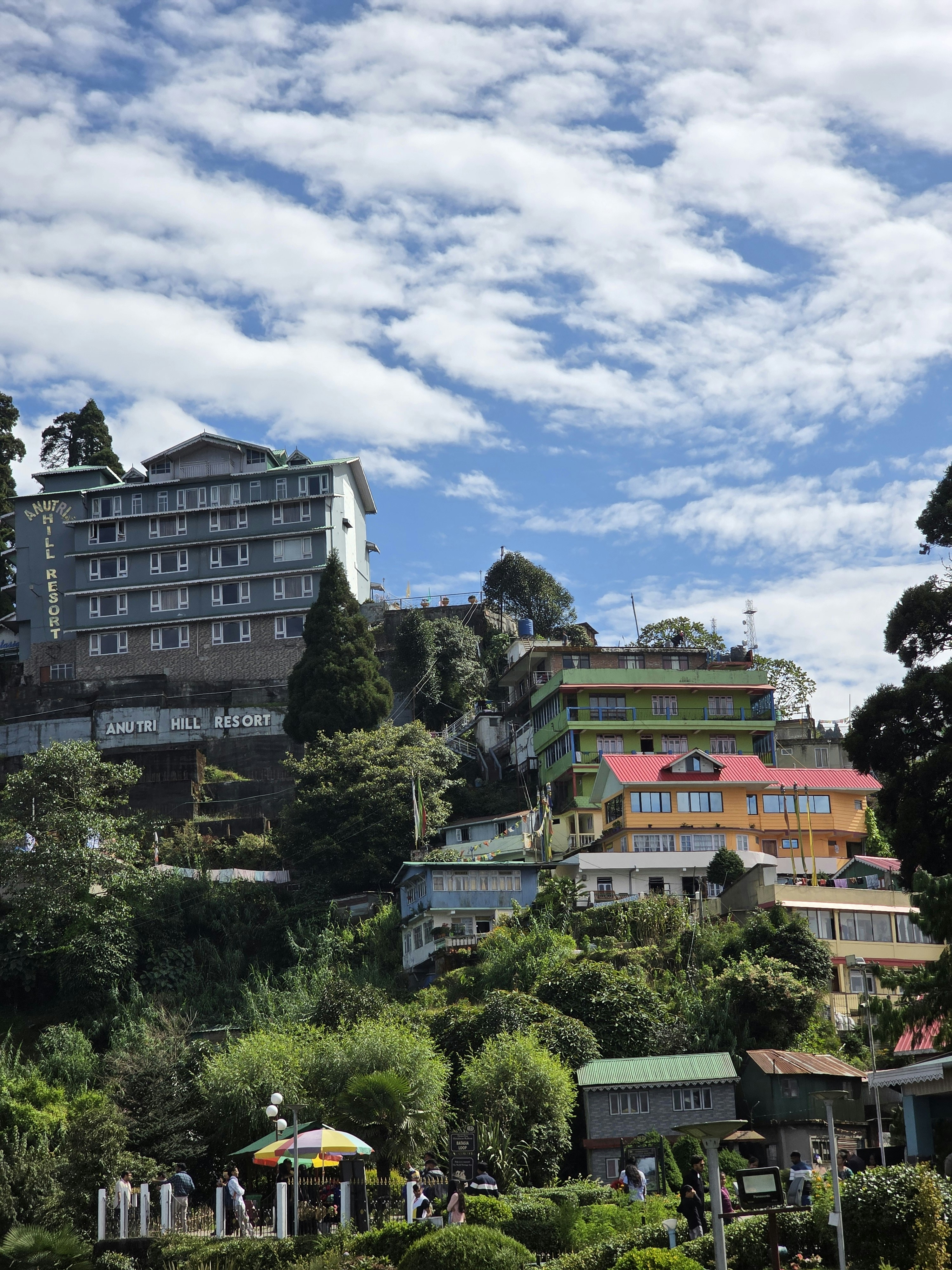Buildings nestled on a lush green hillside under clouds