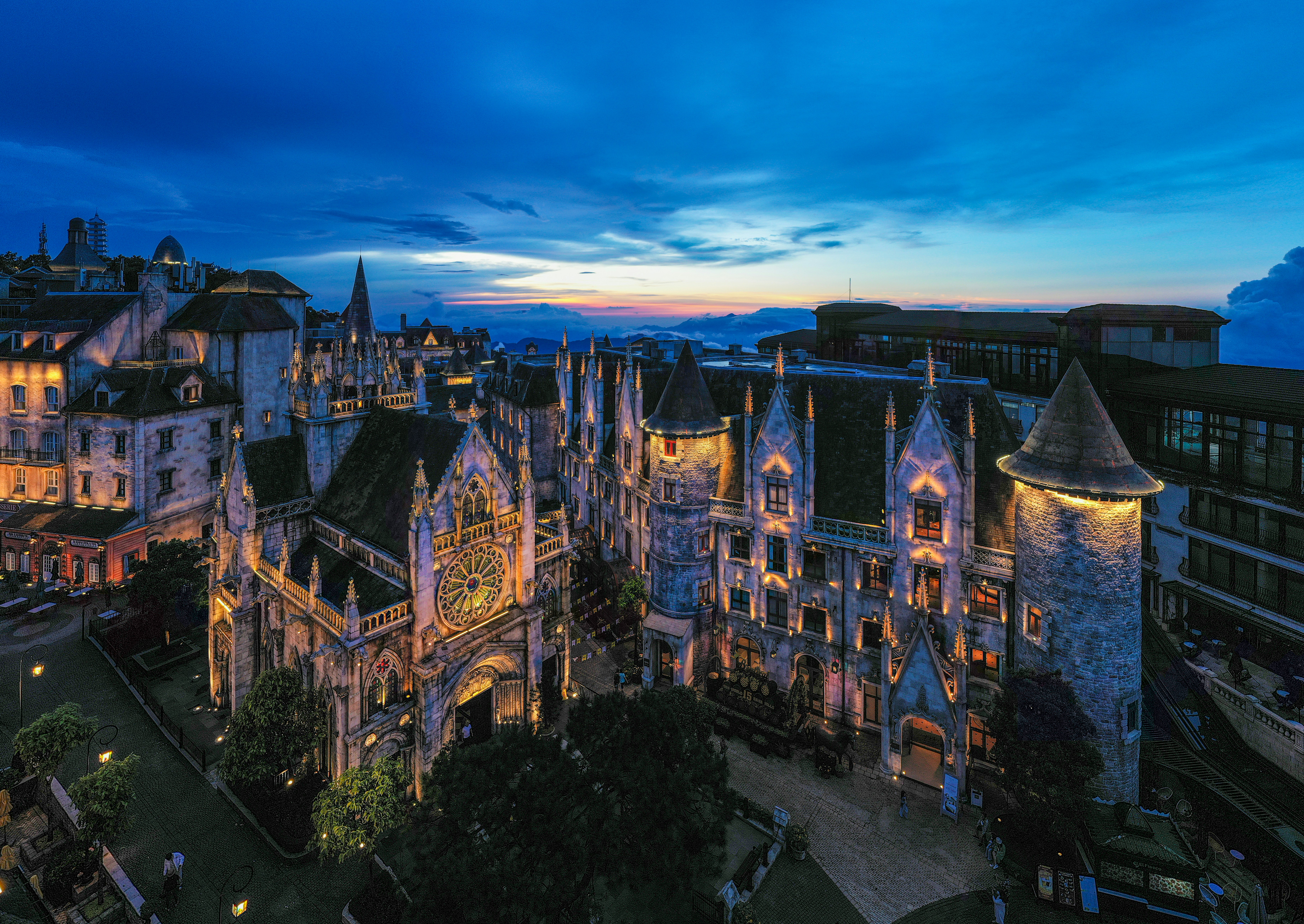 Edifícios históricos ornamentados iluminados ao entardecer com céu dramático