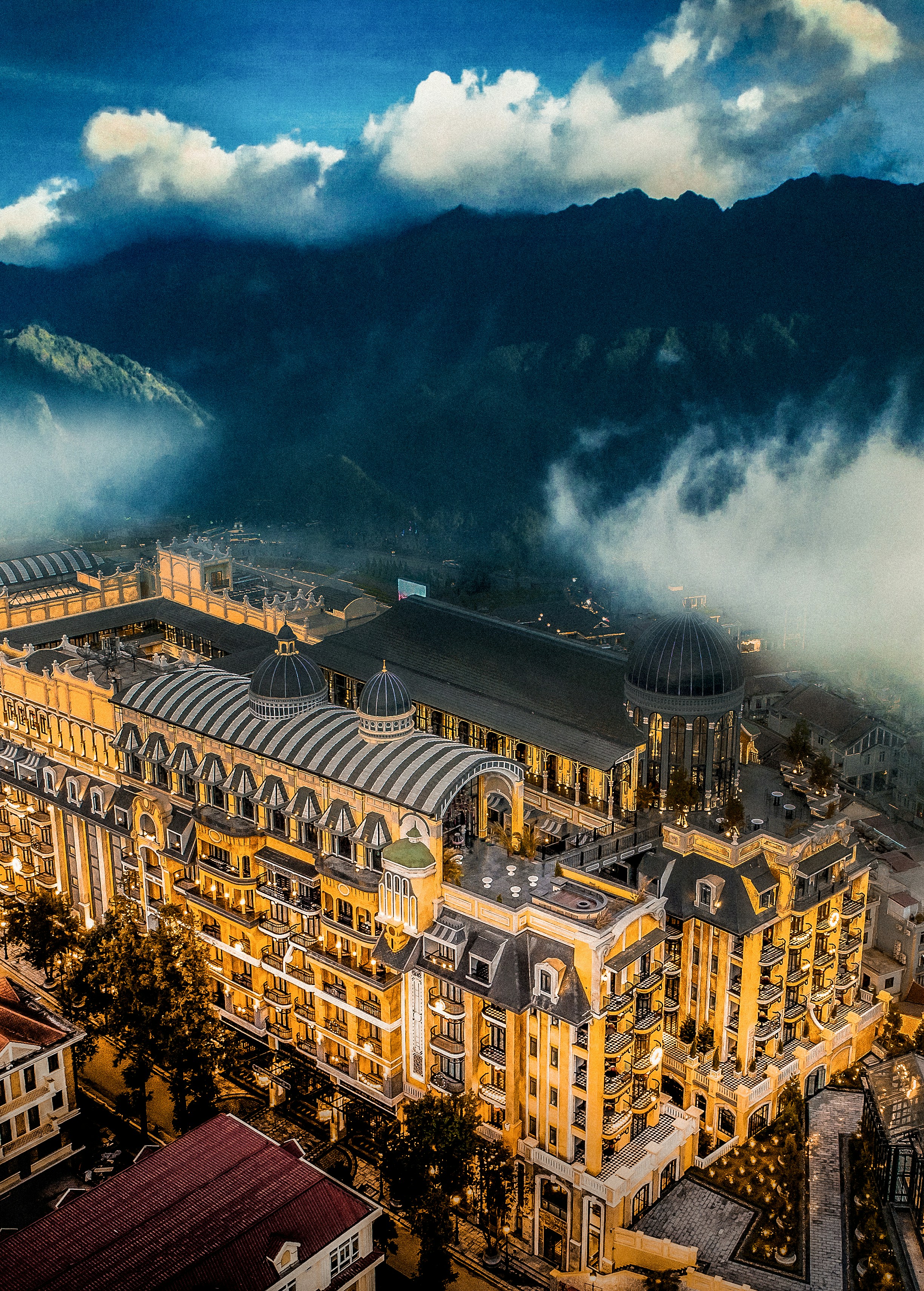 Hotel luxuoso aninhado em montanhas enevoadas ao anoitecer.