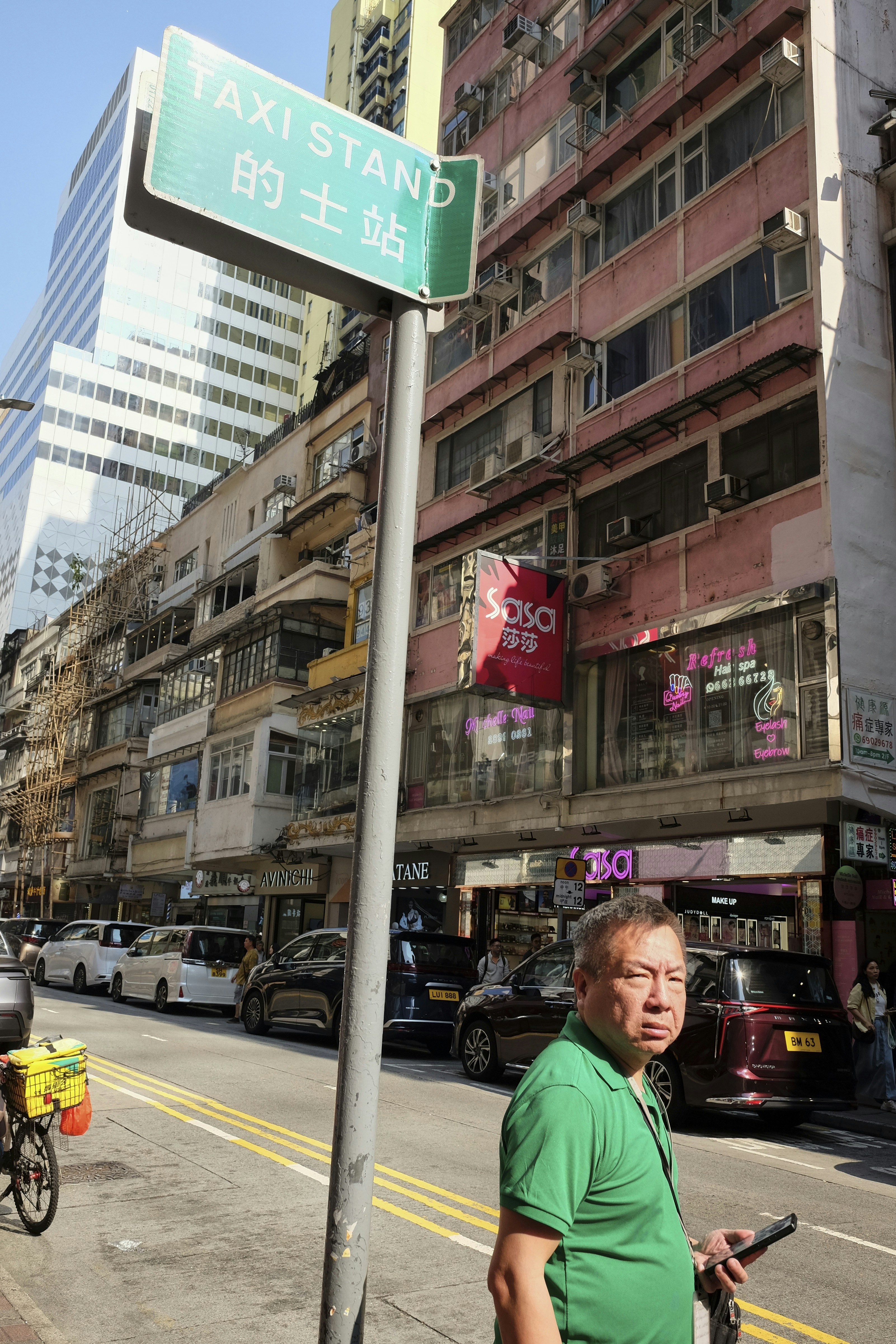 Man standing on street with taxi stand sign