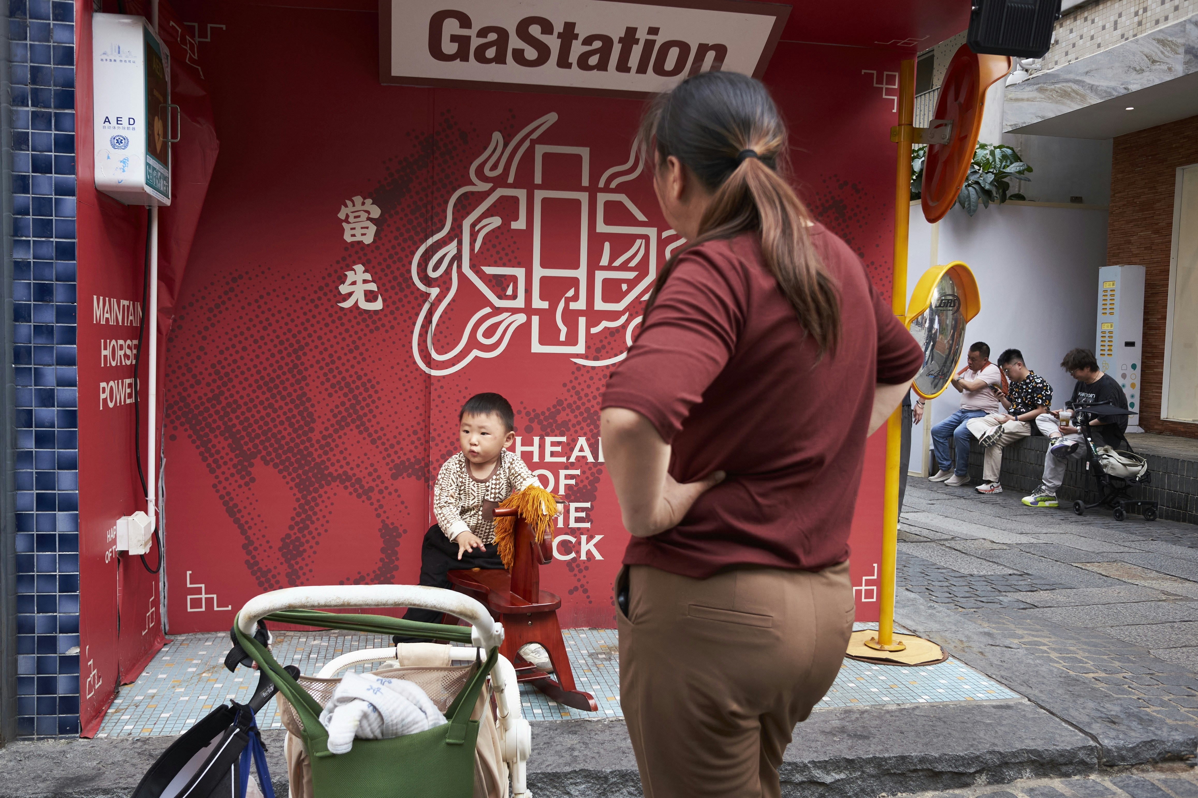 Woman watches child on rocking horse near stroller