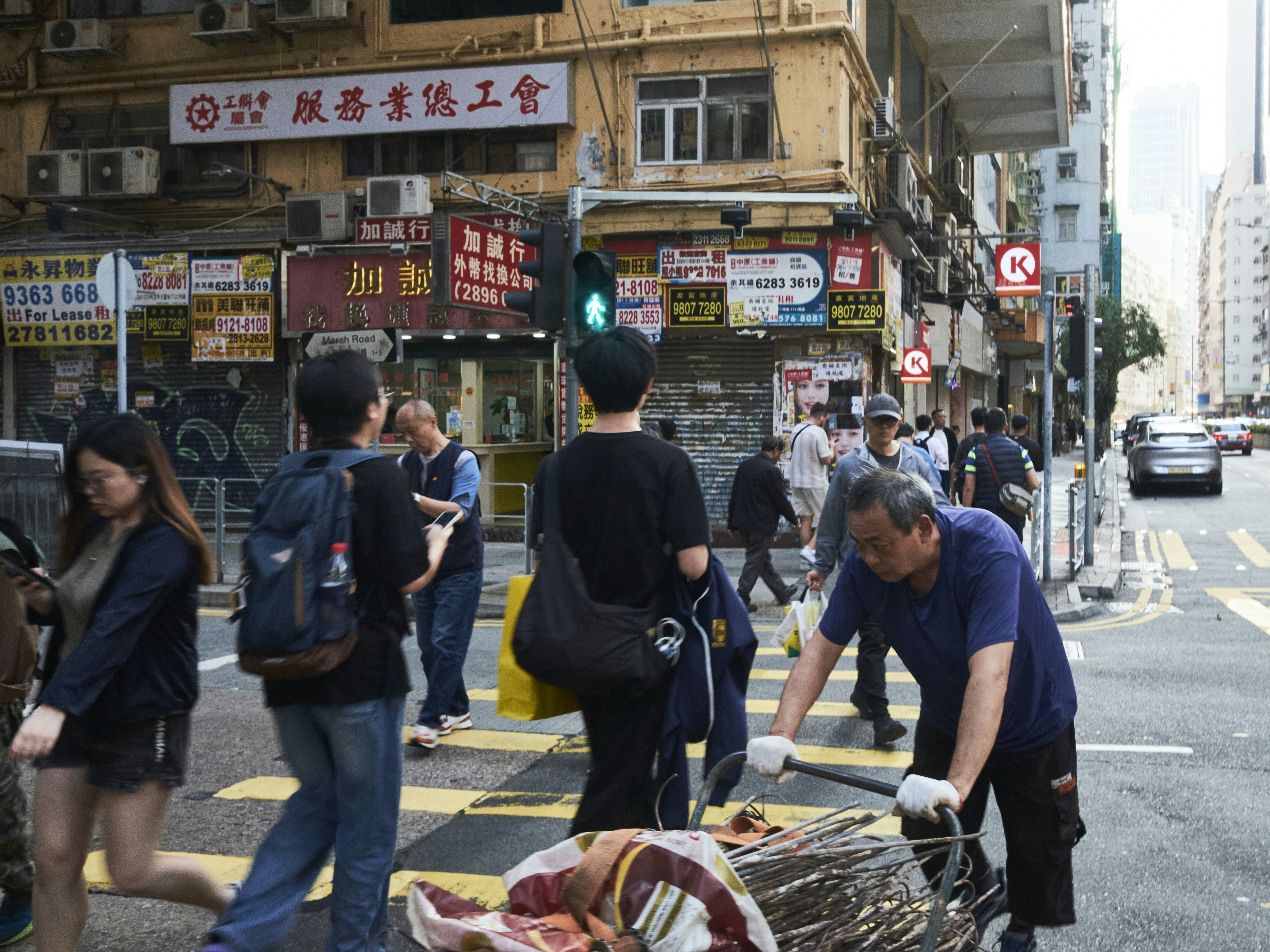People crossing a busy city street with shops.