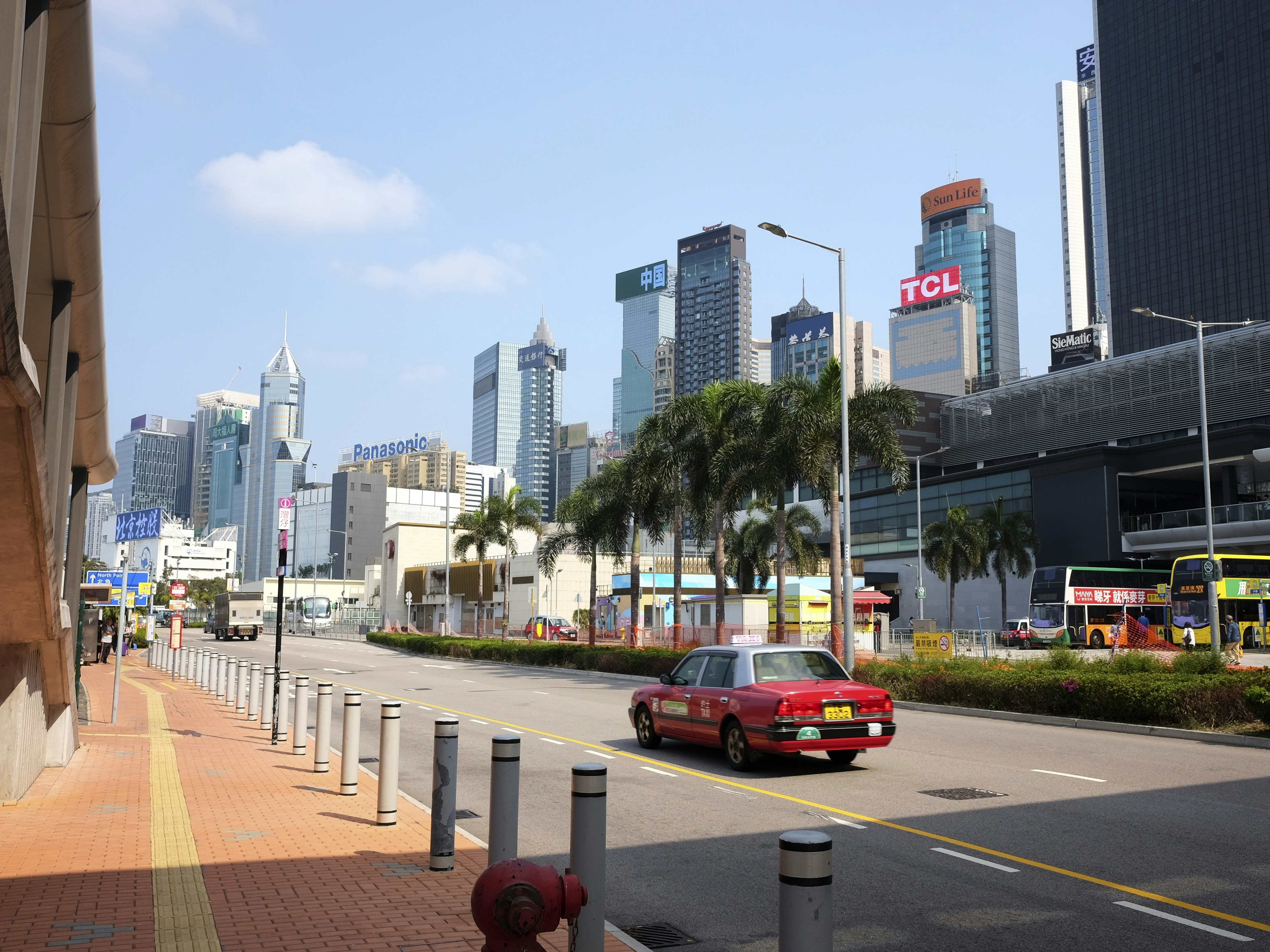 Red taxi drives down a city street with skyscrapers.