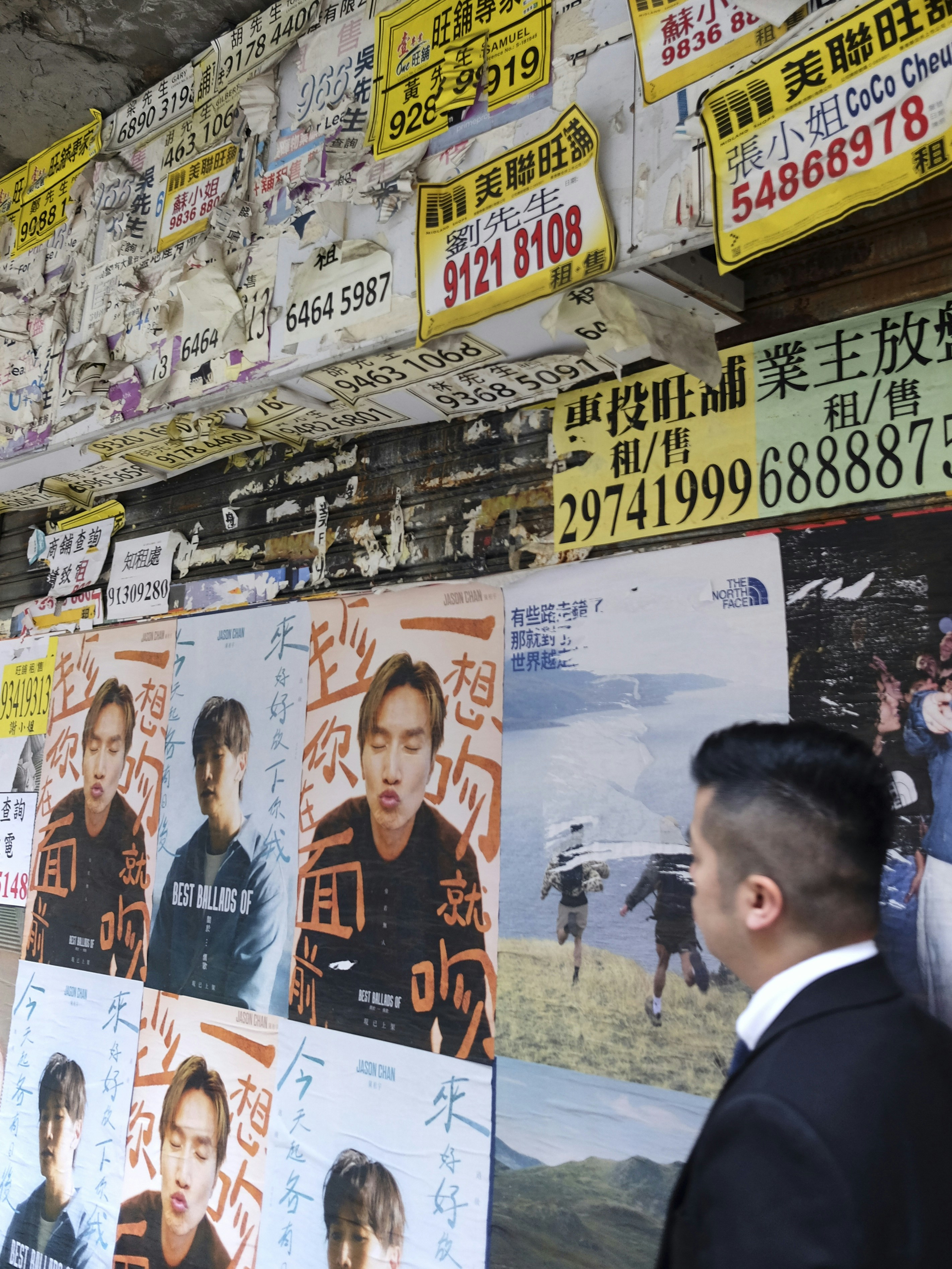 Man looks at posters on a wall covered with flyers.