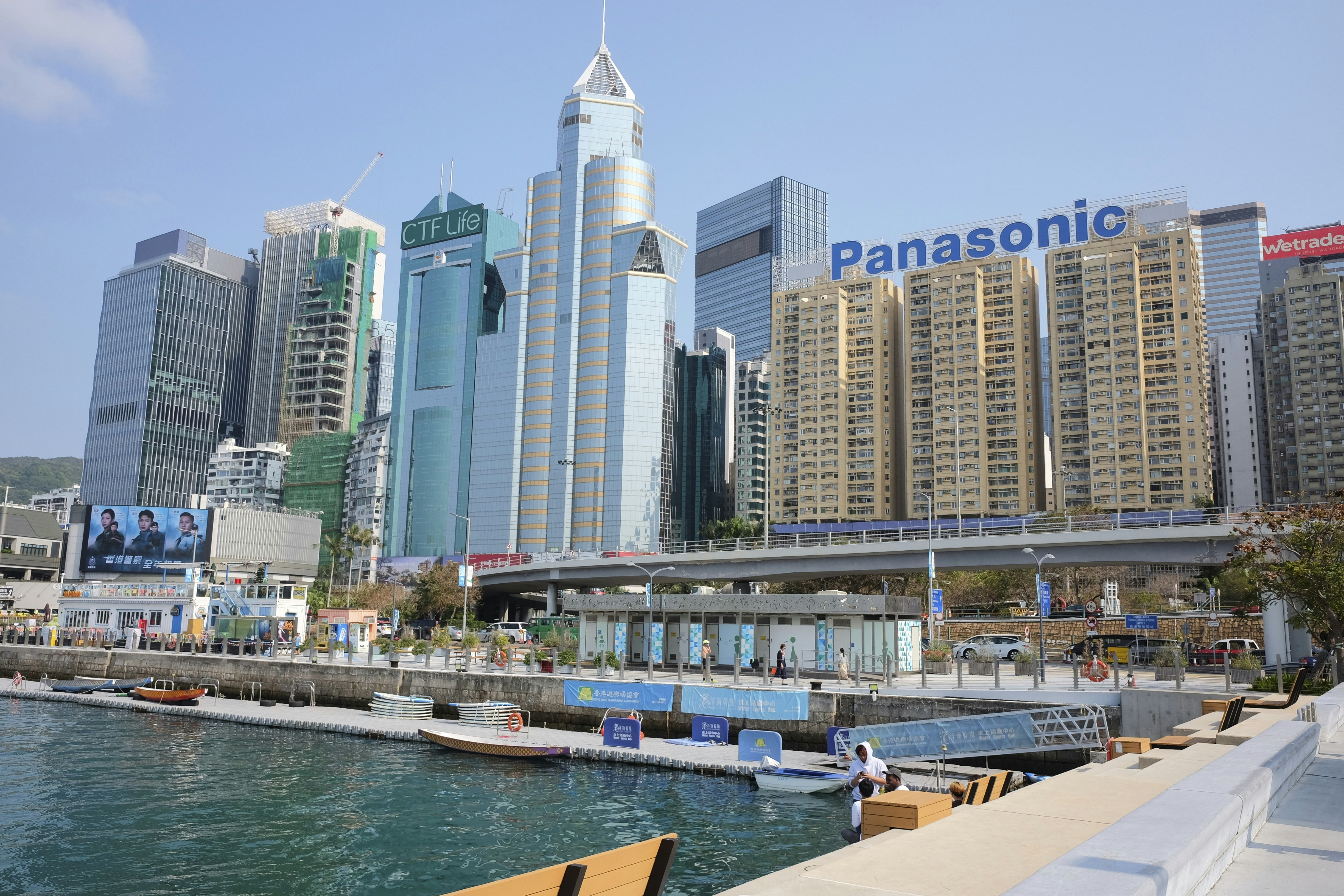 Modern skyscrapers line a waterfront with boats on the water.