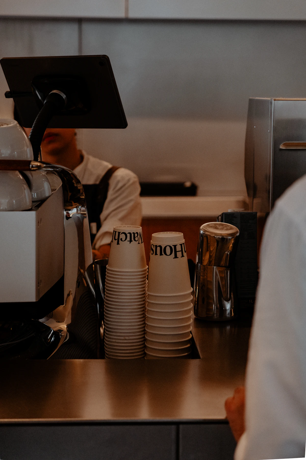 Tumpukan gelas kopi di atas meja kasir sebuah kedai kopi.