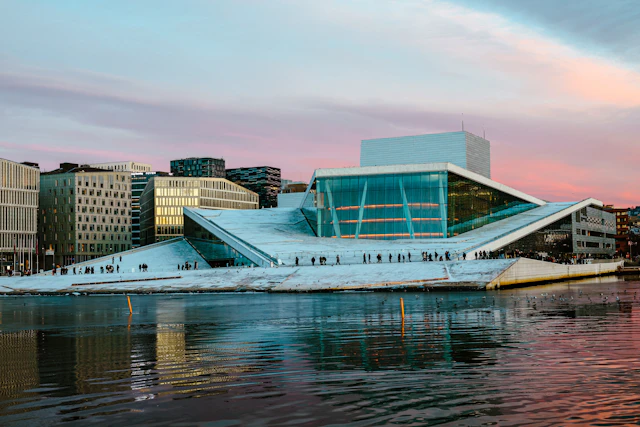 Oslo Opera House with its sloping white roof and glass facade beside the harbour