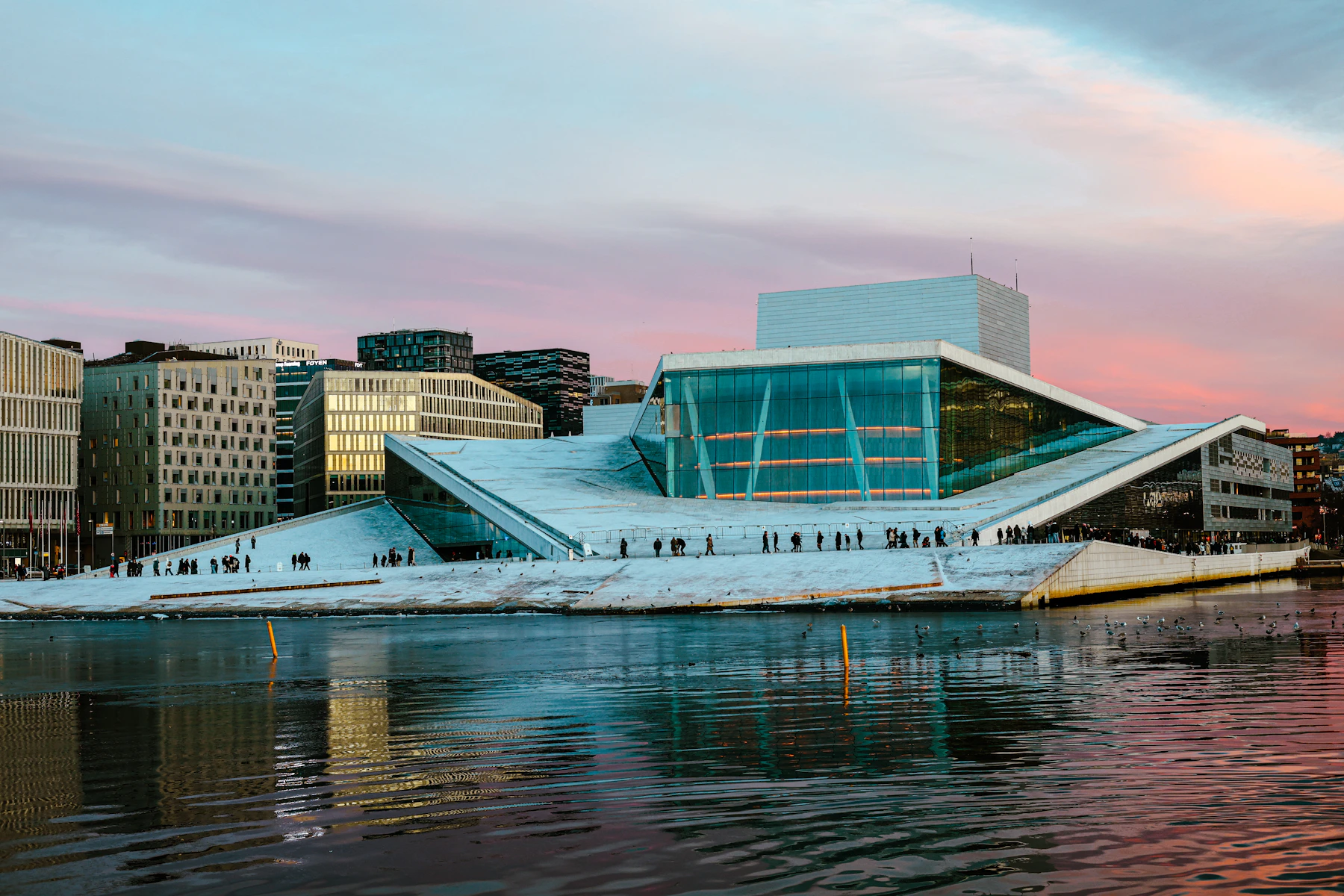 Oslo Opera House with its sloping white roof and glass facade beside the harbour