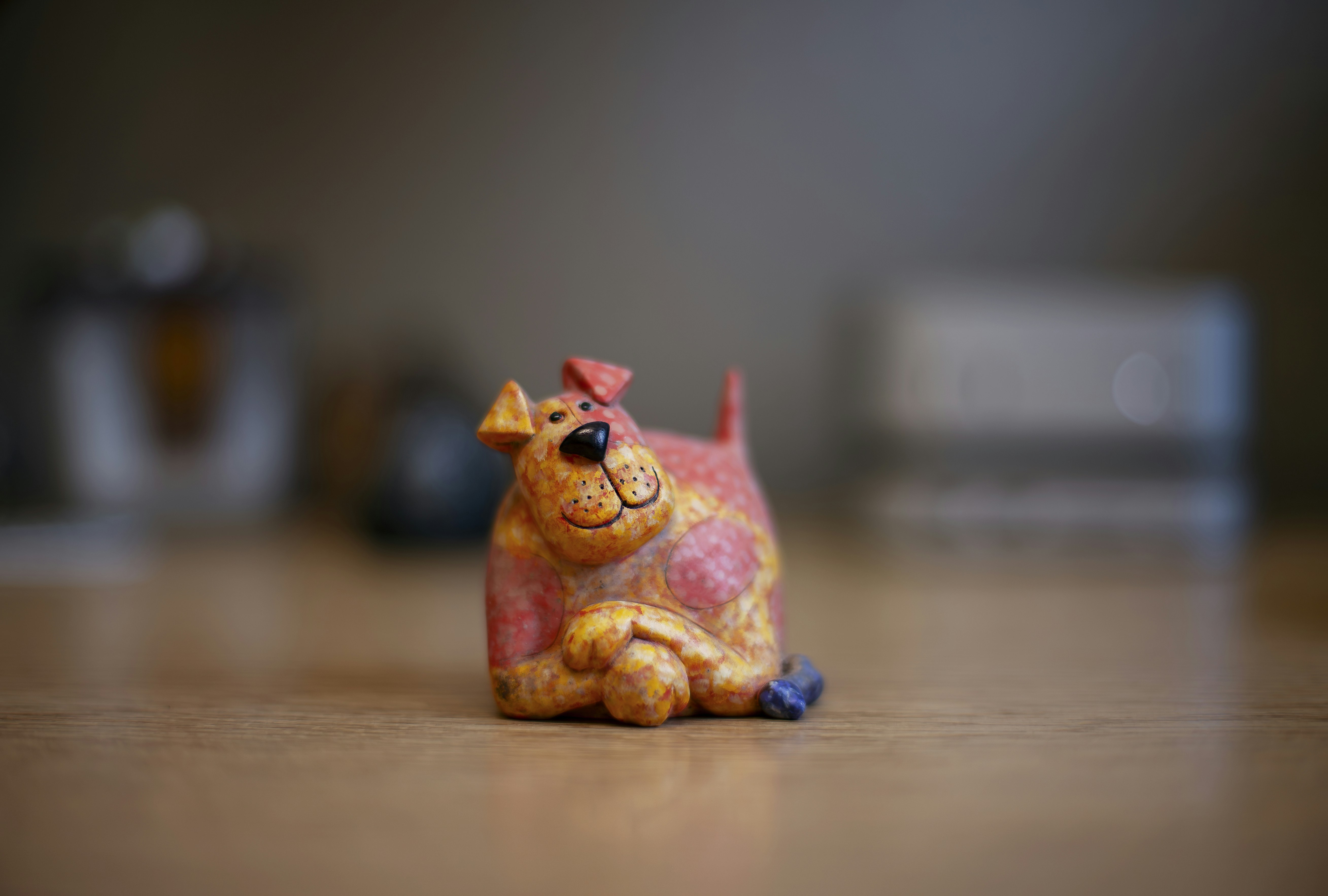 A small, whimsical dog figurine rests on a wooden surface.