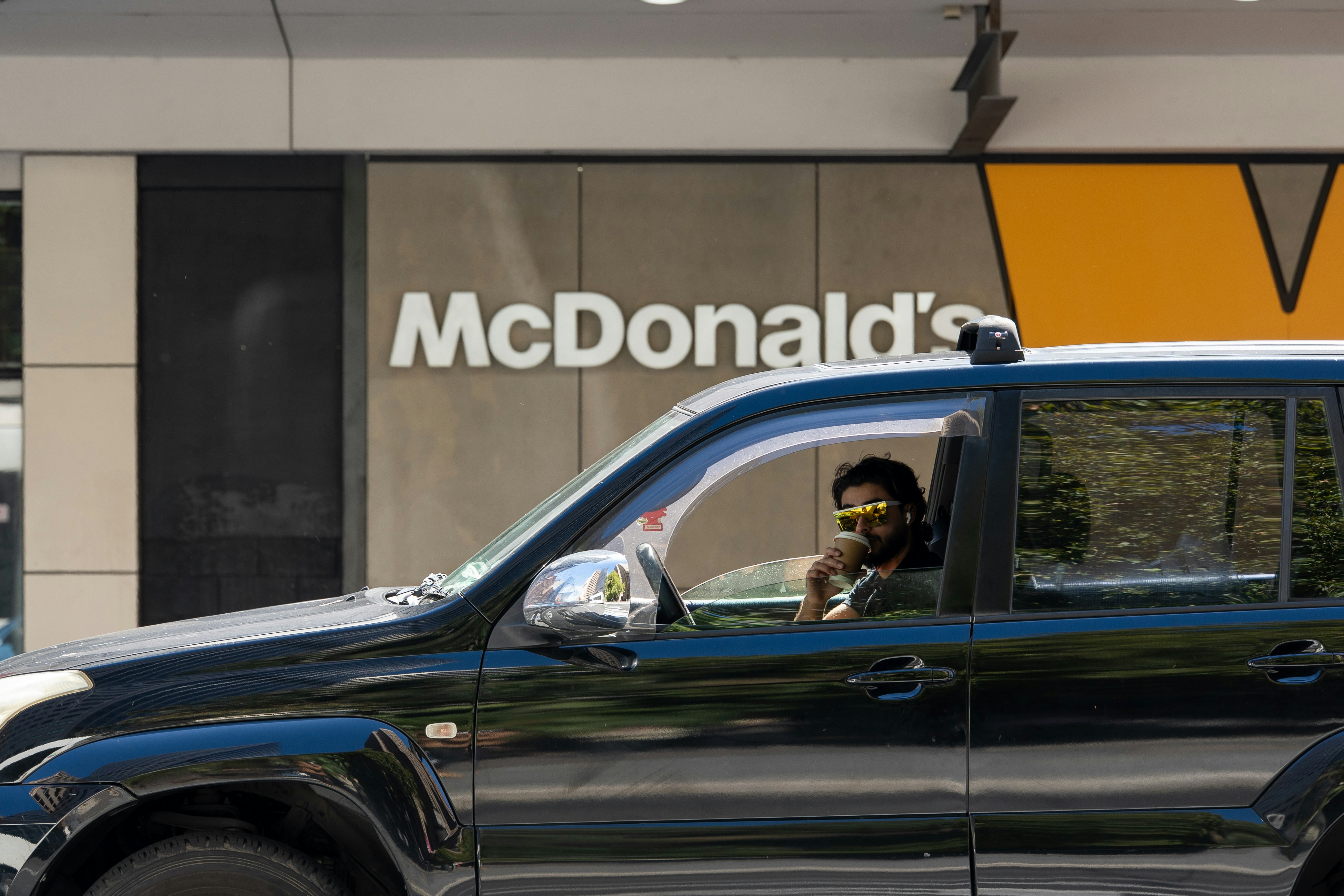 Un homme en voiture passe devant le restaurant McDonald’s.