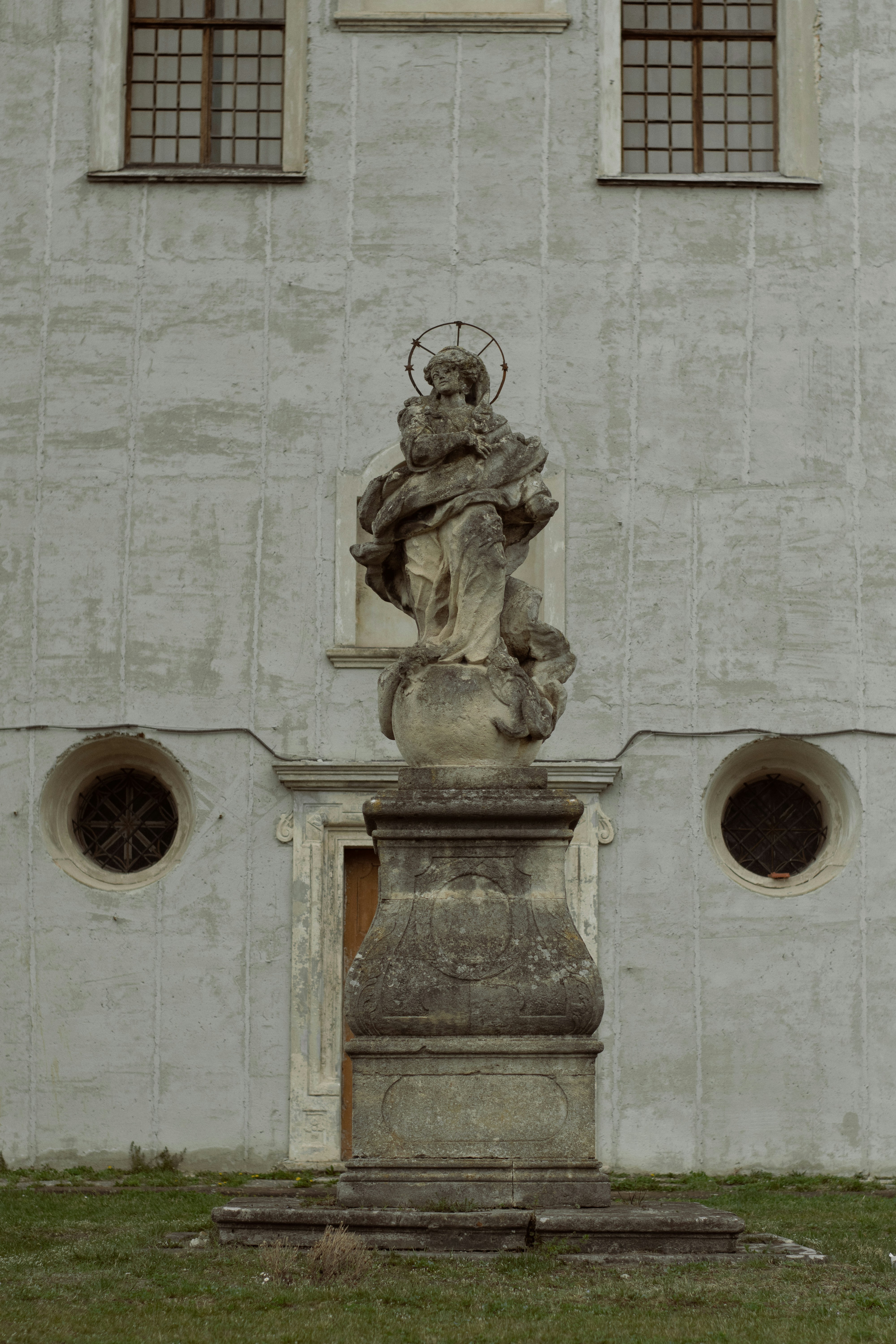 Estatua de piedra de una figura religiosa frente al edificio.