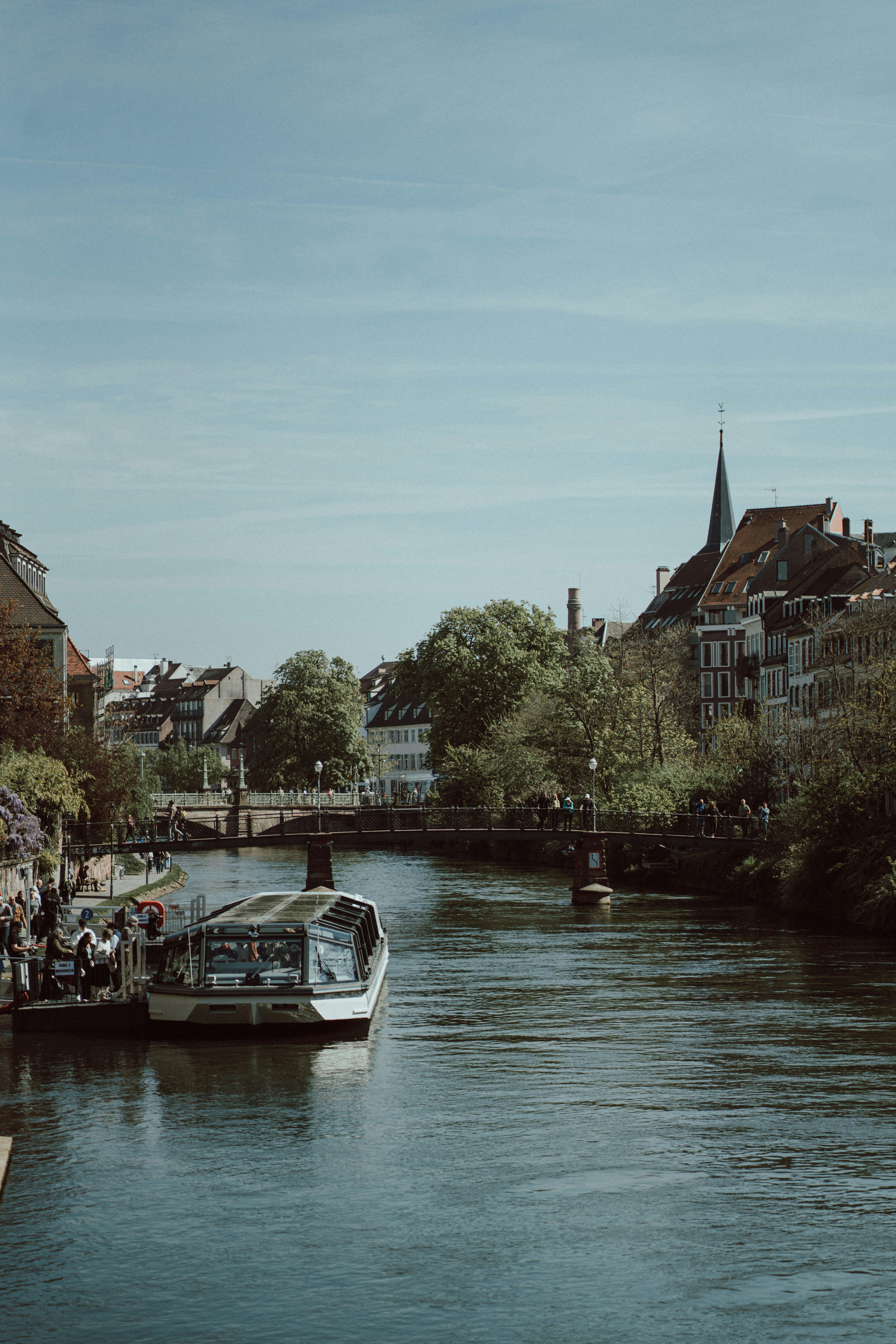 Boat docked on a canal with buildings and bridge.
