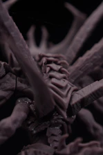 Close-up of a dark, intricate, alien-like sculpture.