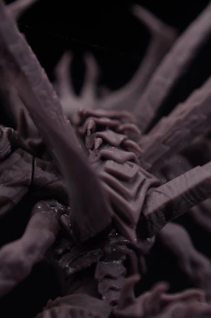 Close-up of a dark, intricate, alien-like sculpture.