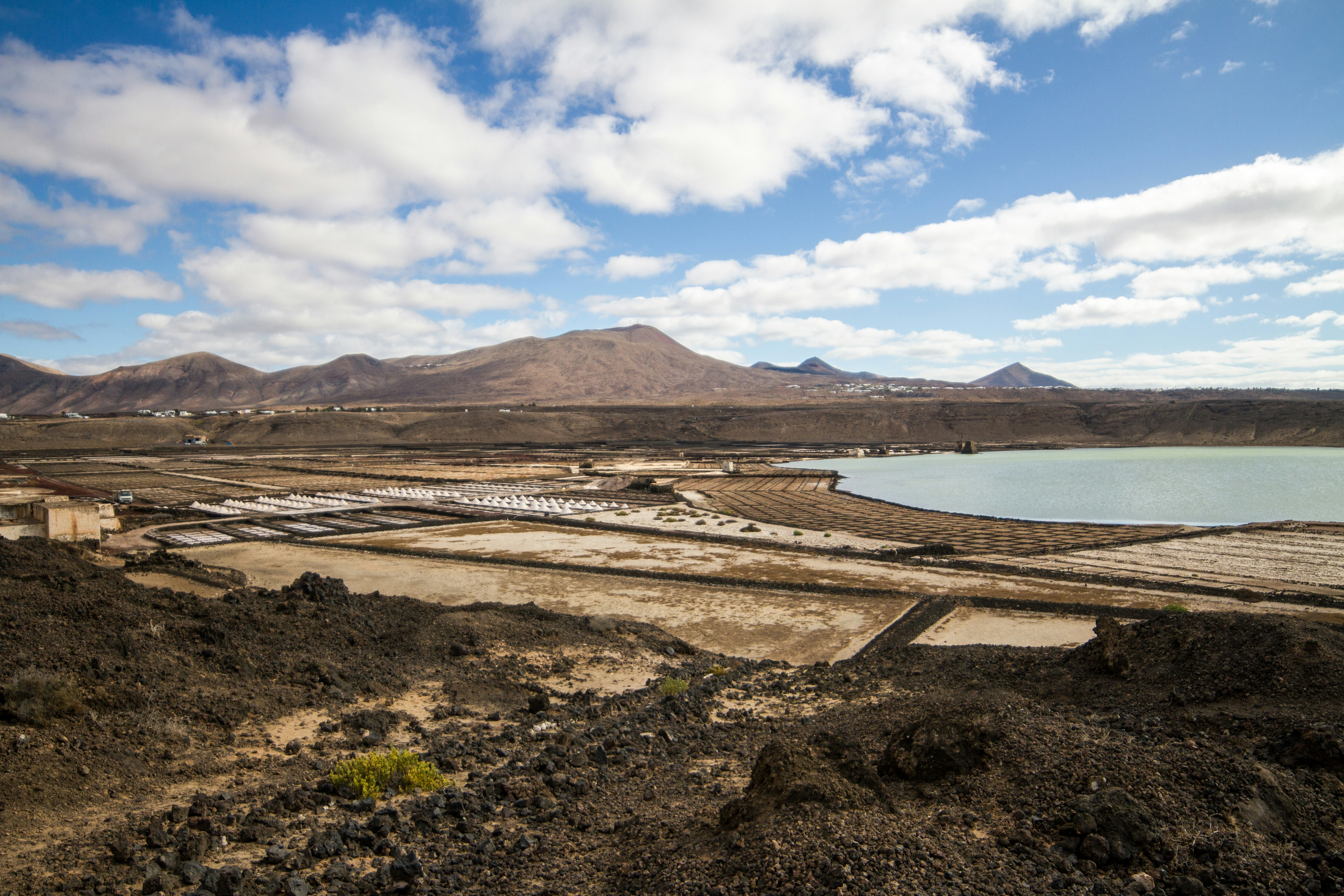 Barren landscape with salt flats and distant mountains.