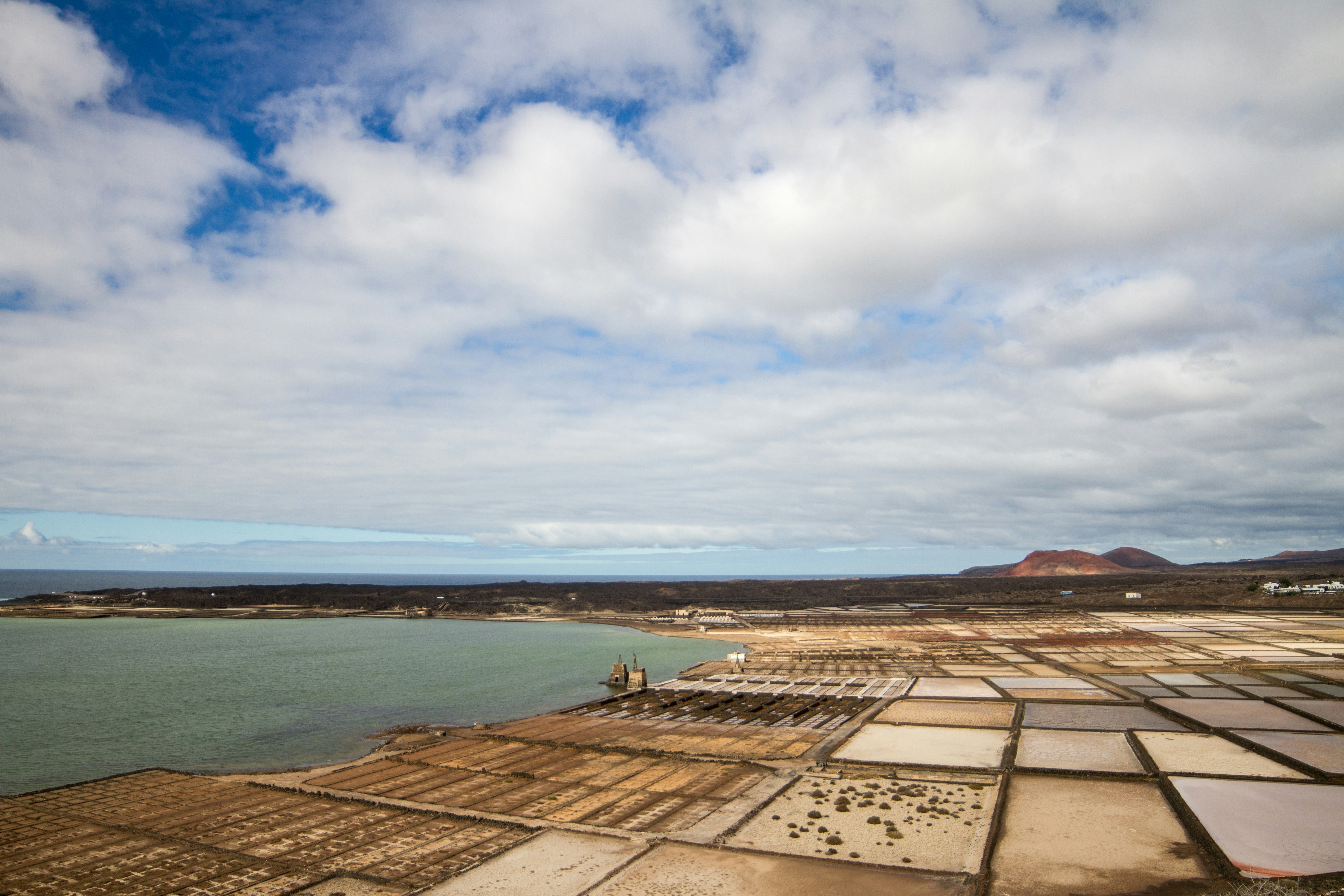 Salt pans with a calm sea under a cloudy sky