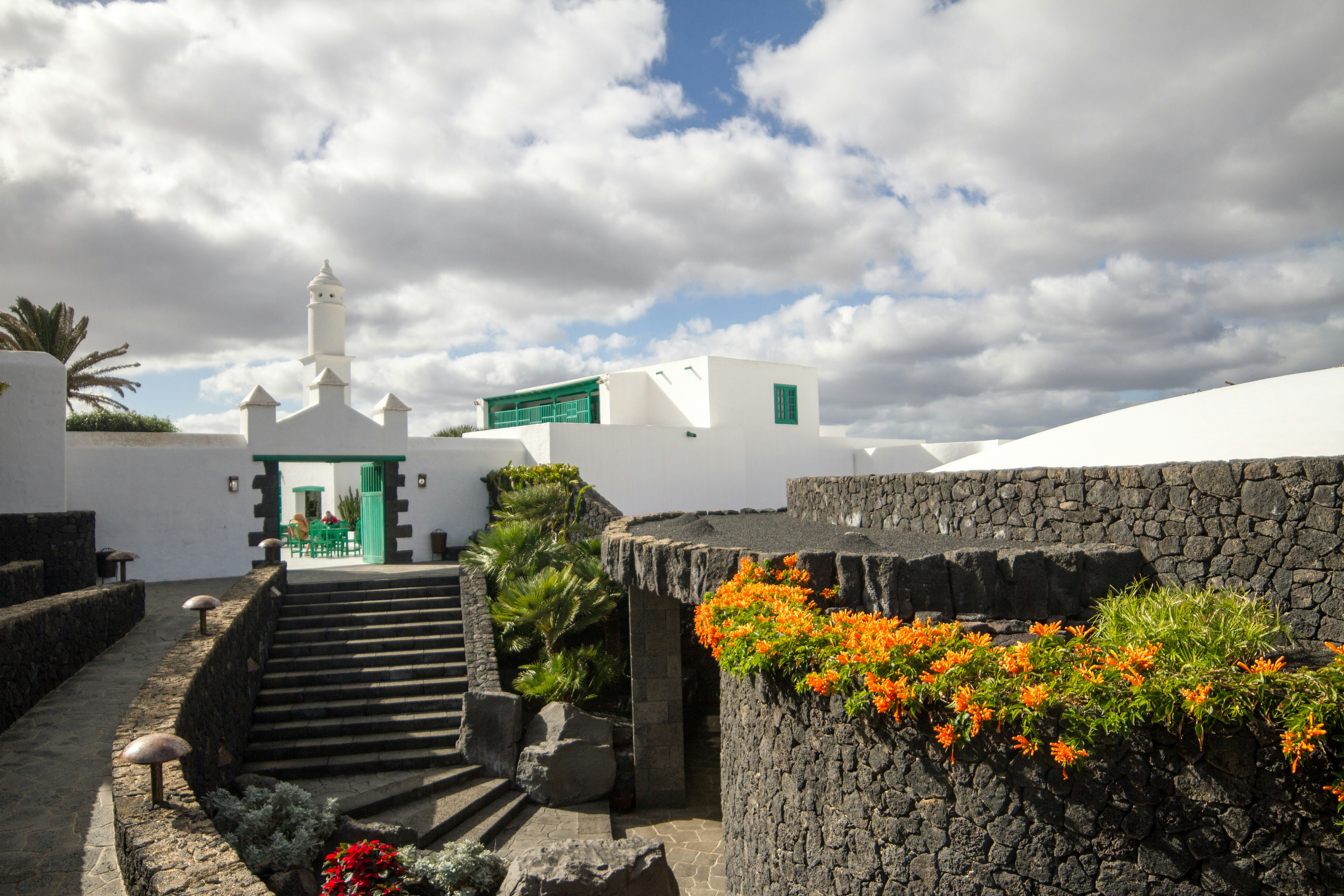 White building with dark stone walls and orange flowers