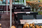Empty outdoor cafe tables and chairs with dry leaves