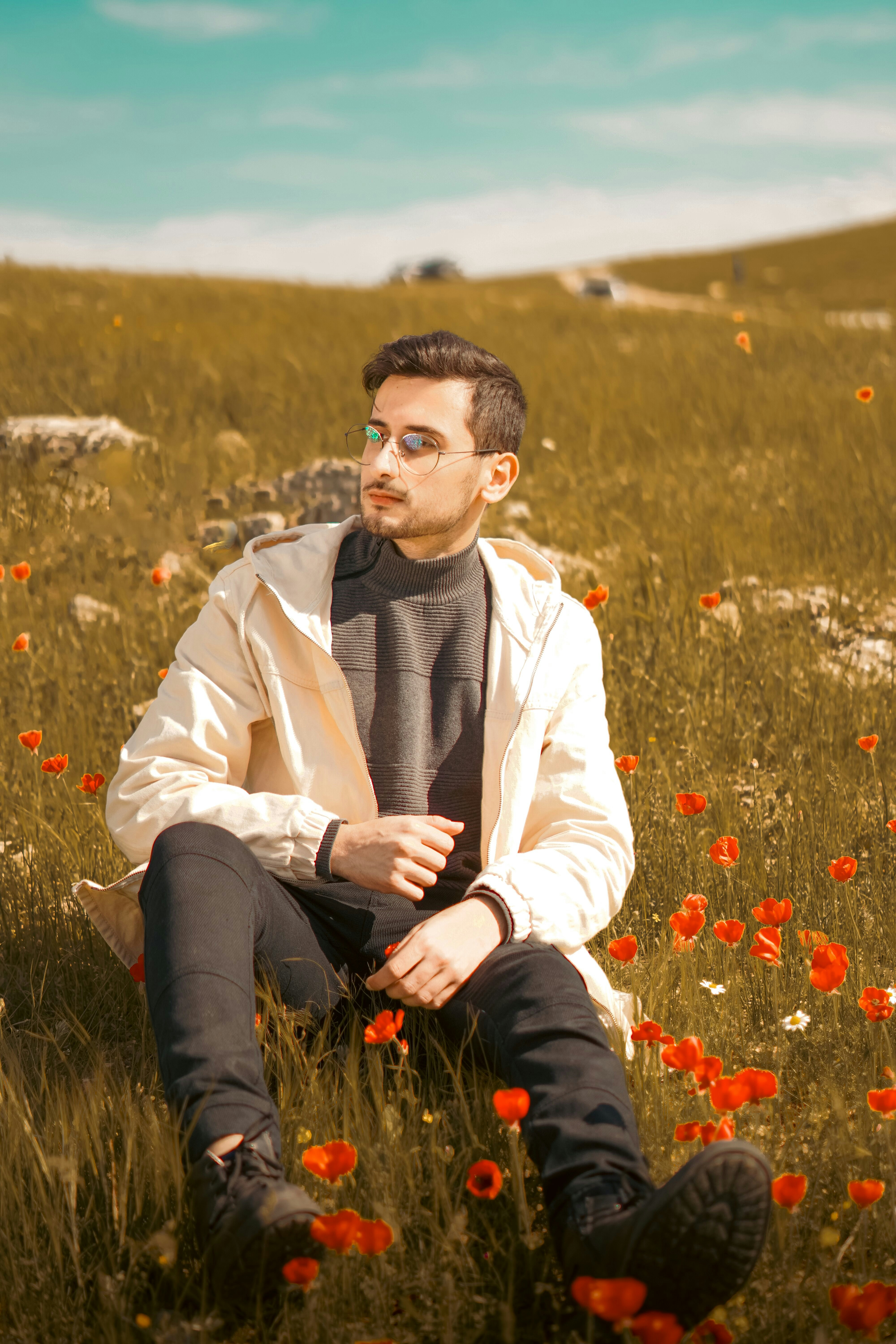 Young man sitting in a field of red poppies