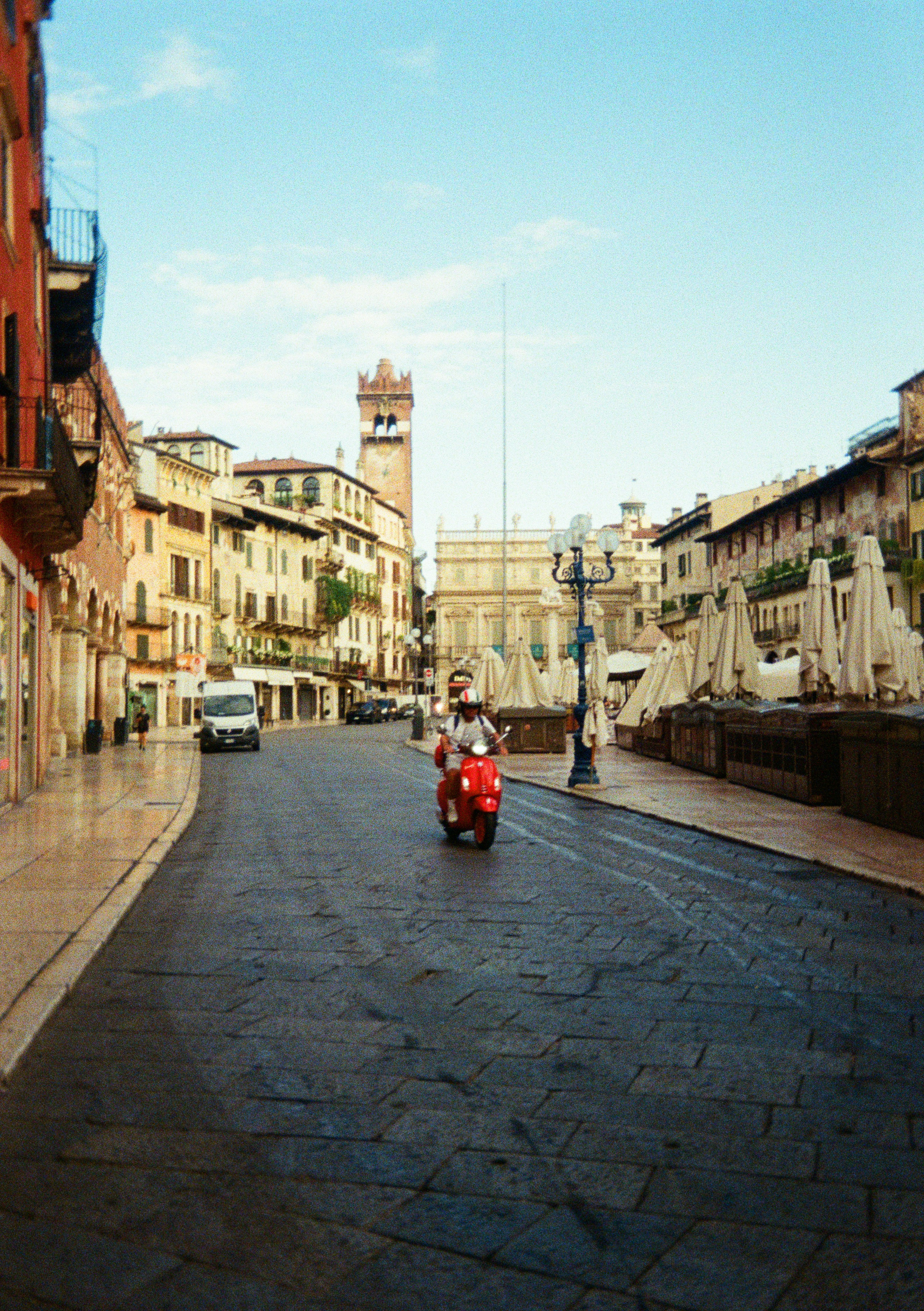 Una persona guida uno scooter rosso su una strada deserta.