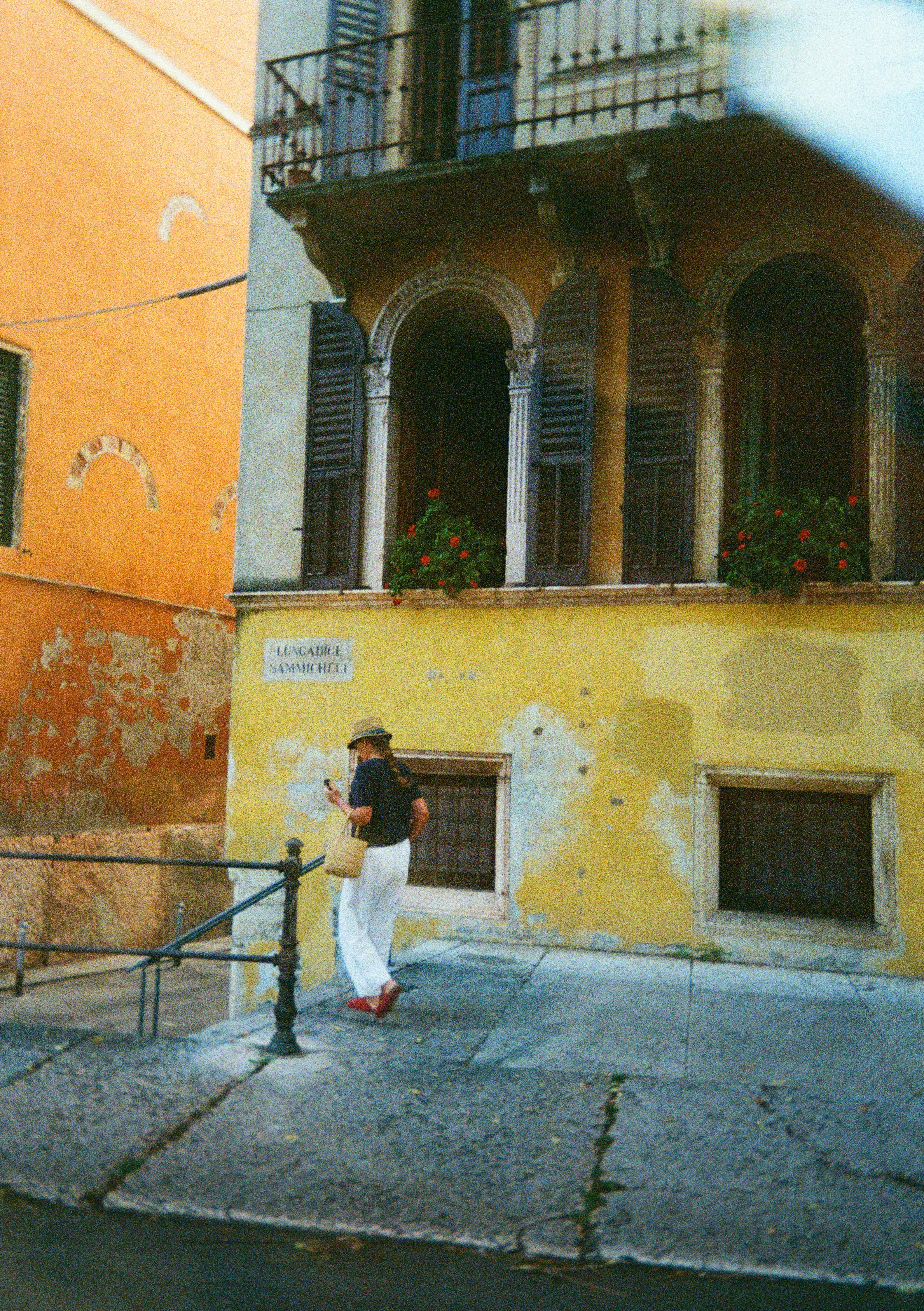 Donna con il cappello passa davanti a un edificio giallo