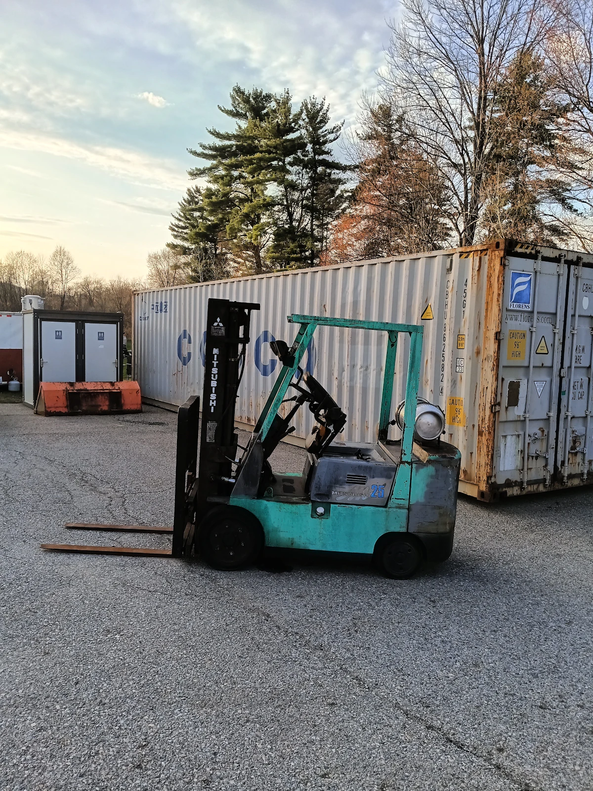 Forklift handling cargo beside shipping containers