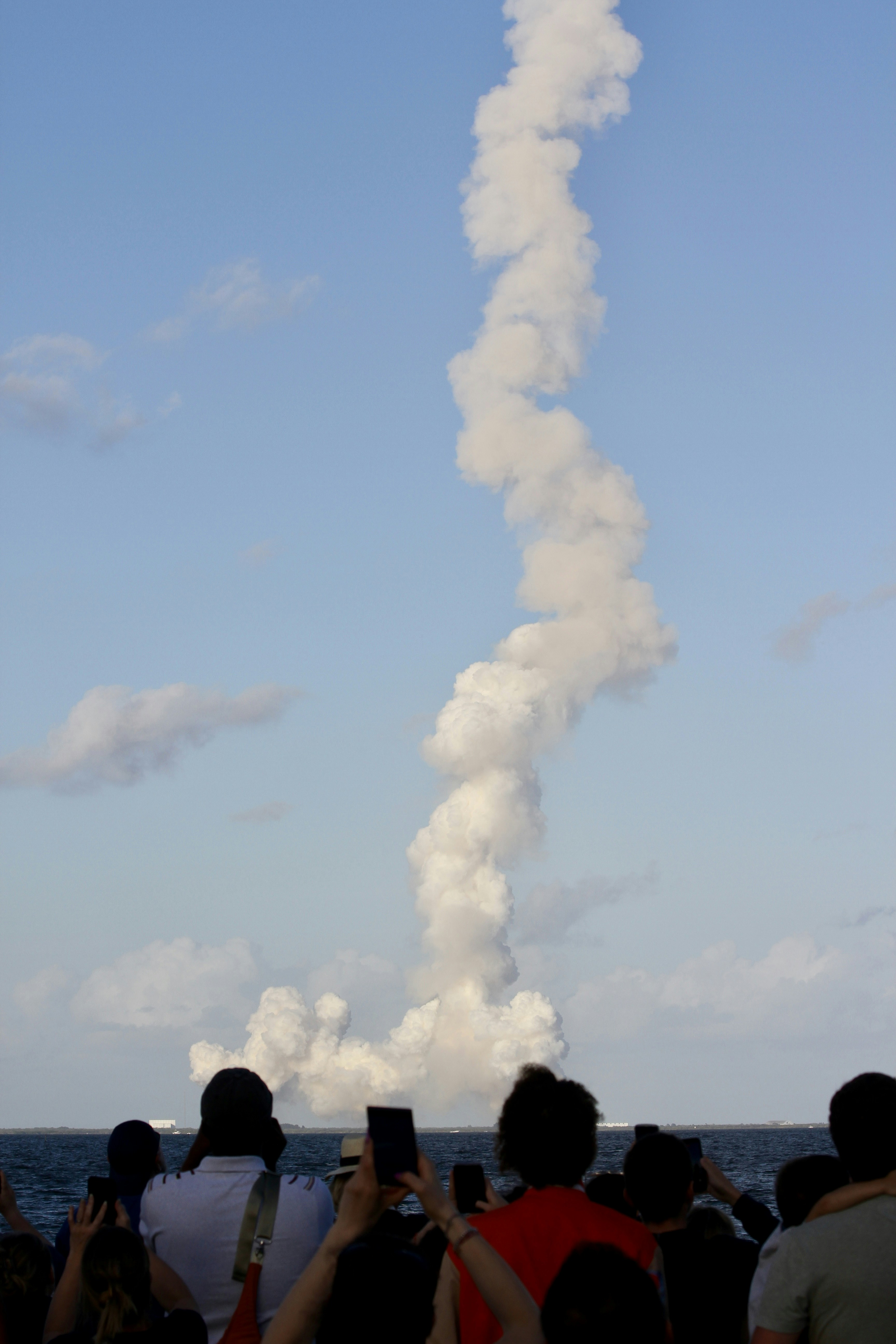 People watch a rocket launch with smoke trail