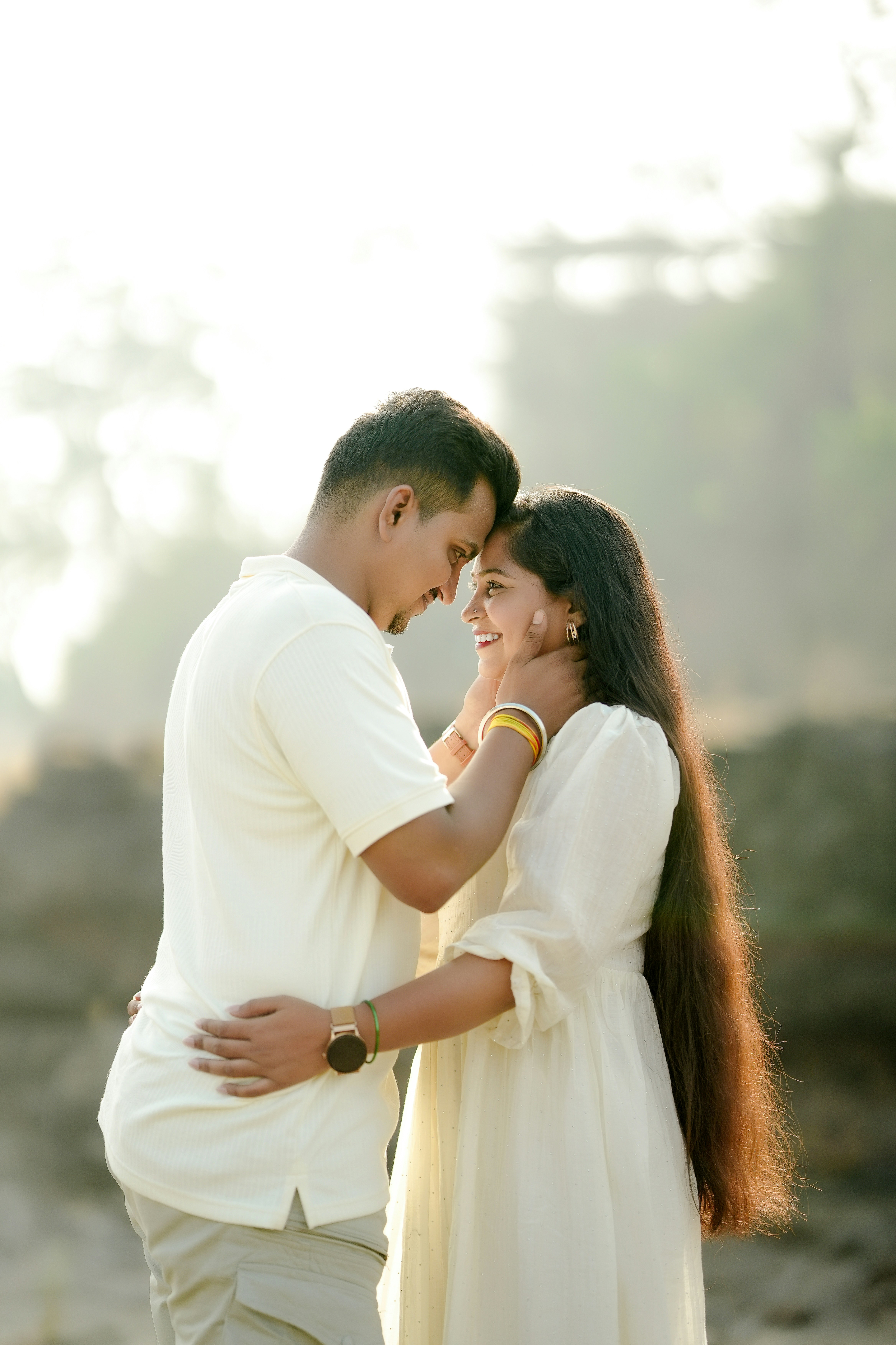 A couple embraces with foreheads touching outdoors