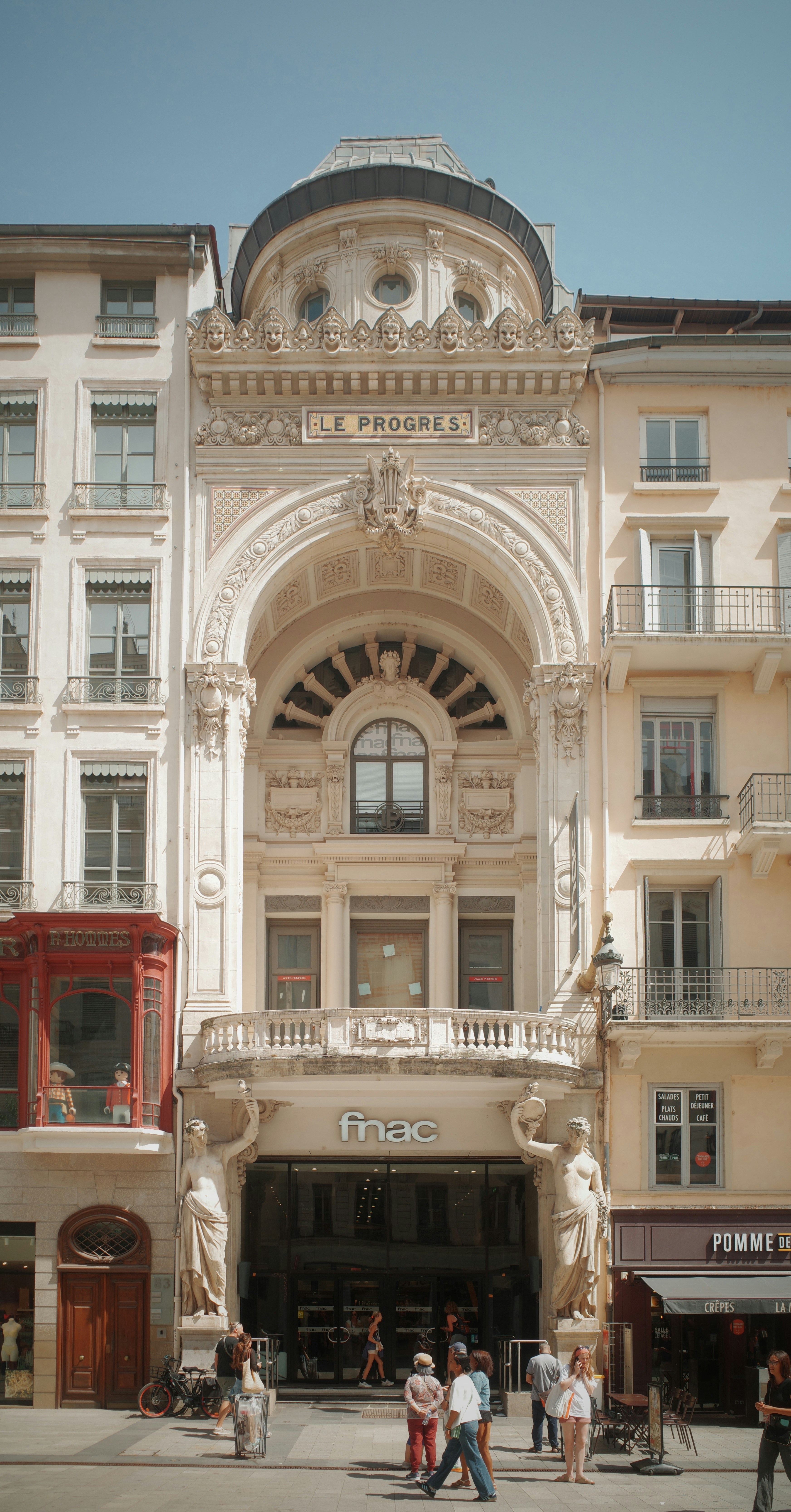 Elaborate building entrance with statues and people outside.
