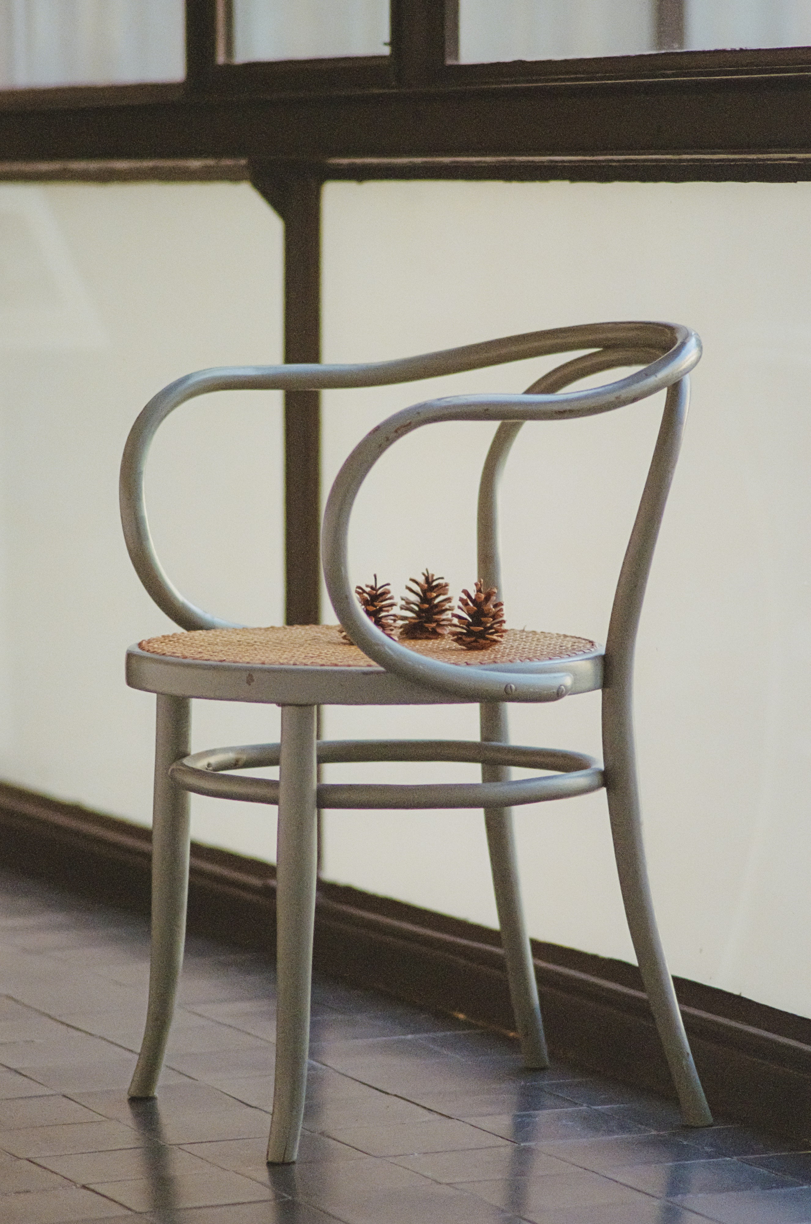 A light grey chair with three pinecones on the seat.
