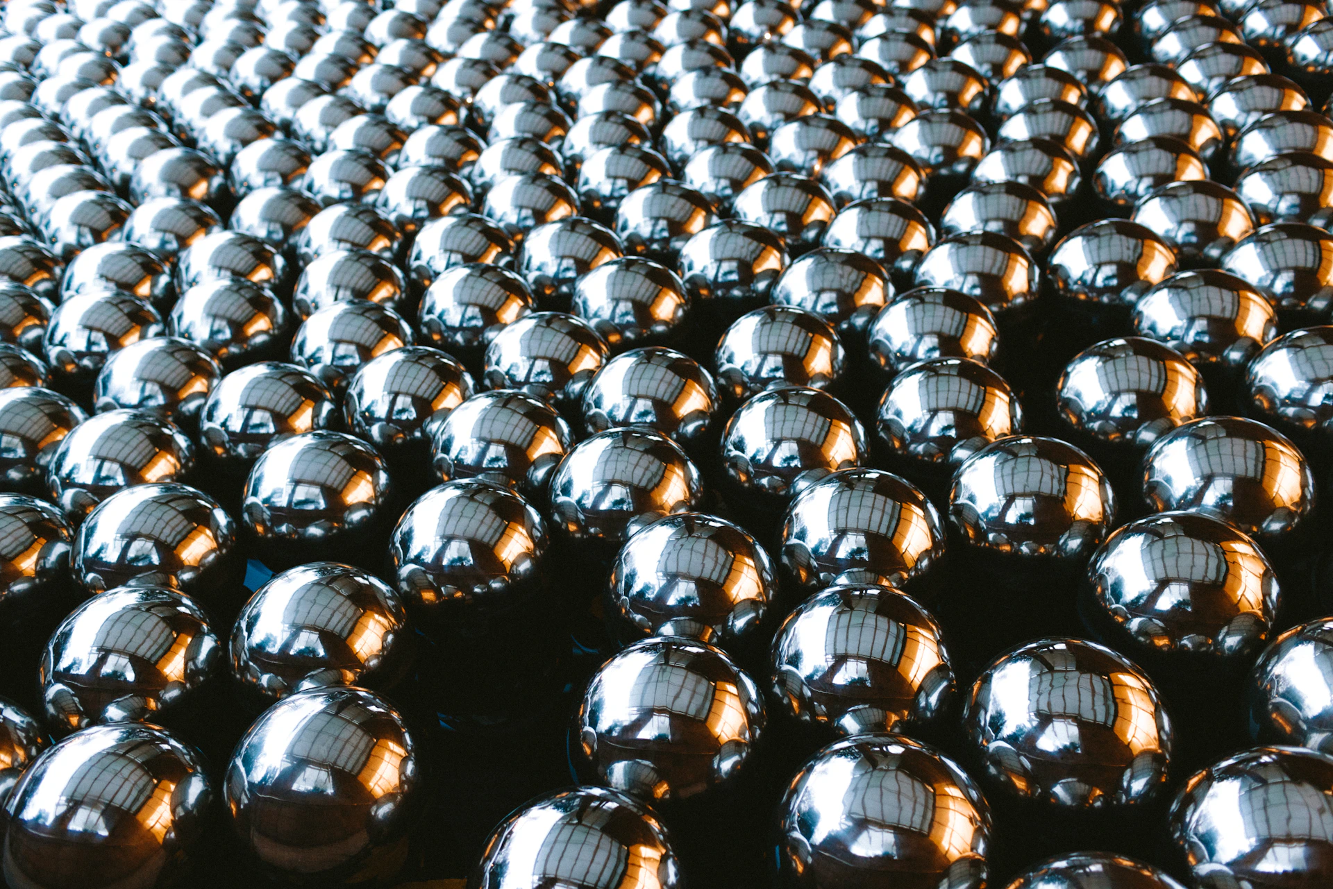 Rows of shiny silver spheres arranged on a dark surface.